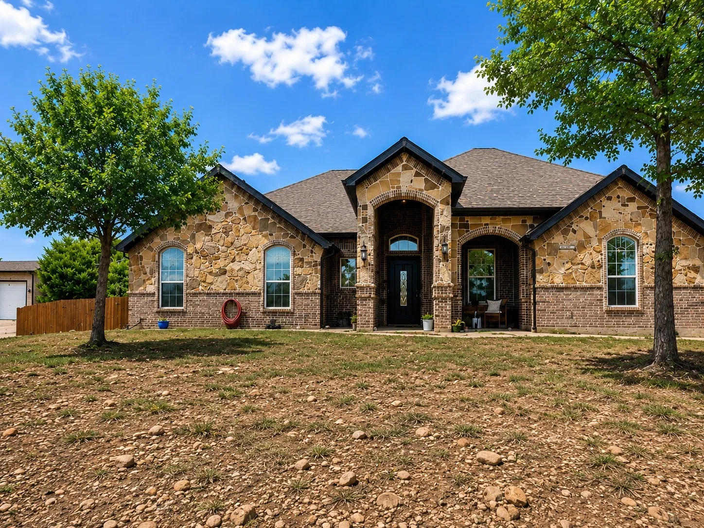 Stone and brick exterior featuring arched entryways and a dark-framed front door with decorative glass