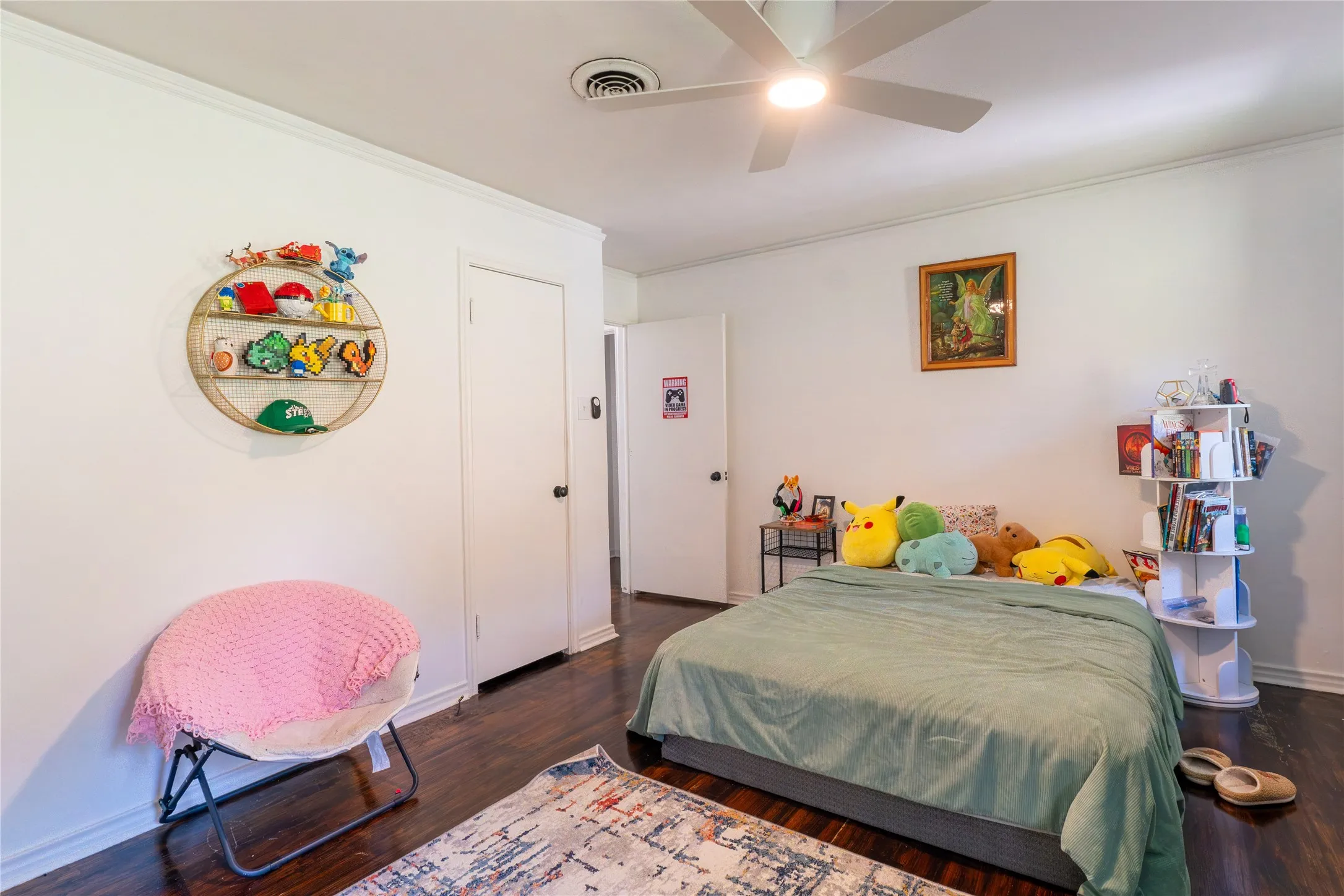 Bedroom with ornamental molding, dark wood-style floors, and a ceiling fan