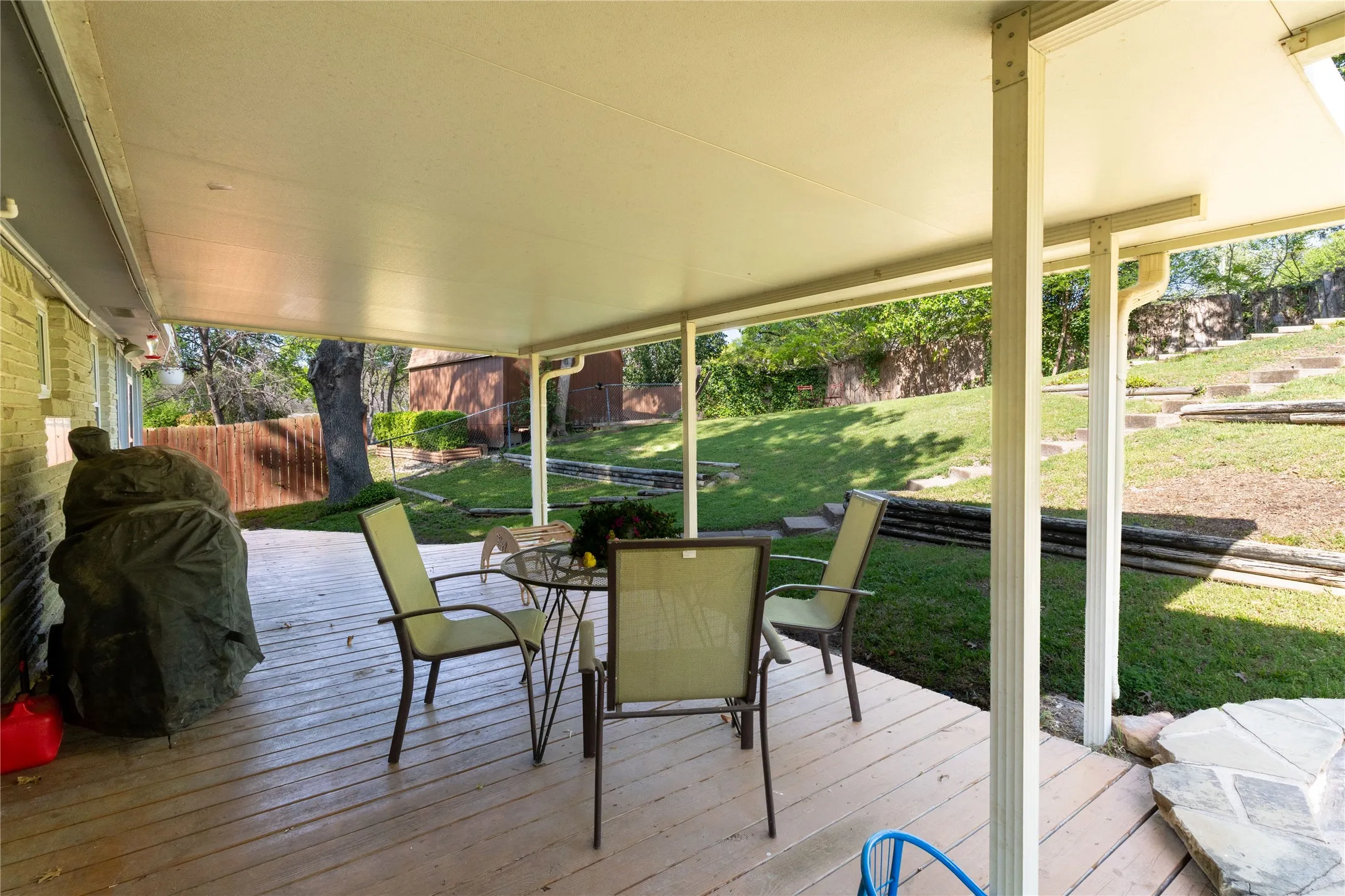 Wooden terrace featuring outdoor dining space, a fenced backyard, and a grill