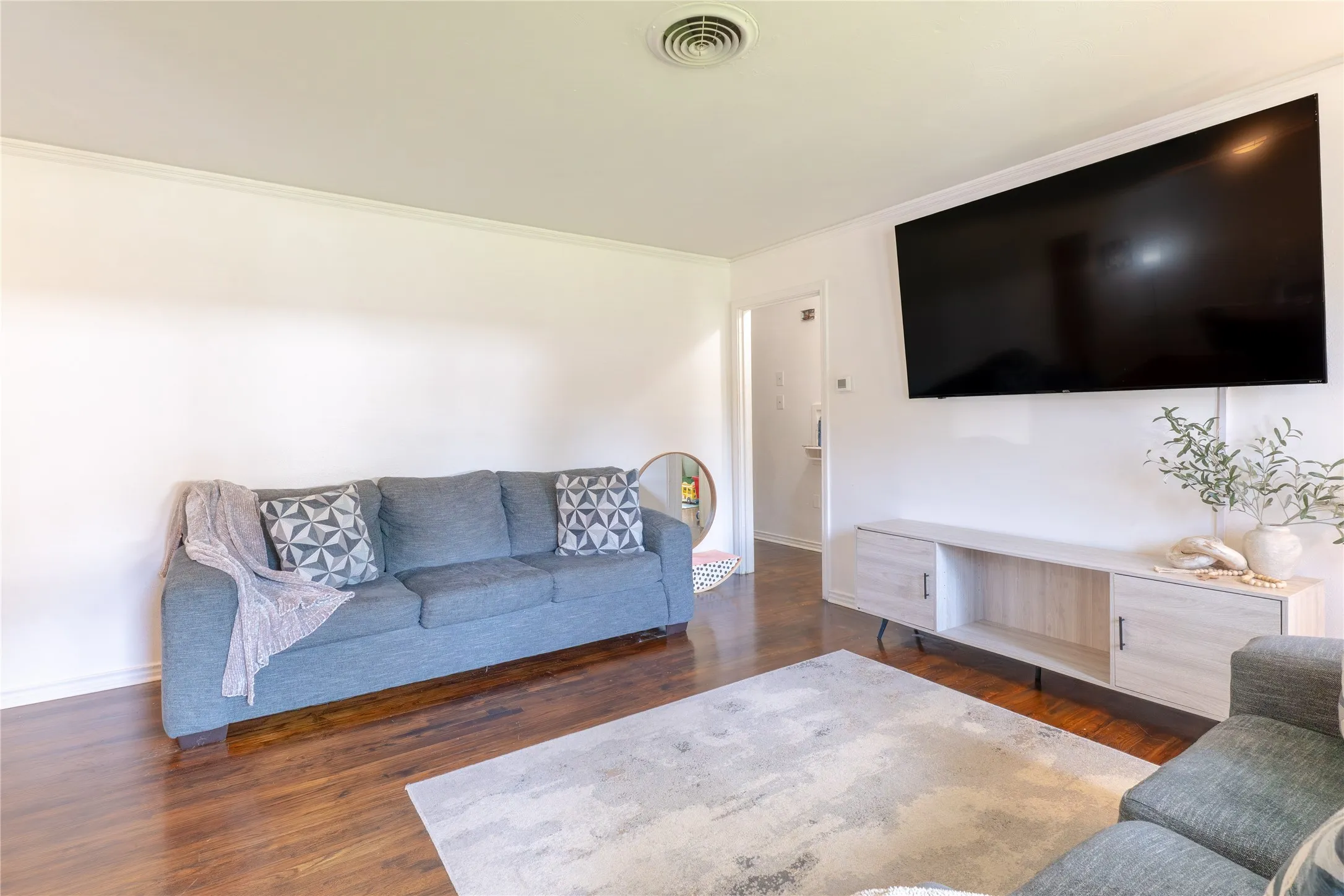 Living room featuring dark wood-type flooring and ornamental molding
