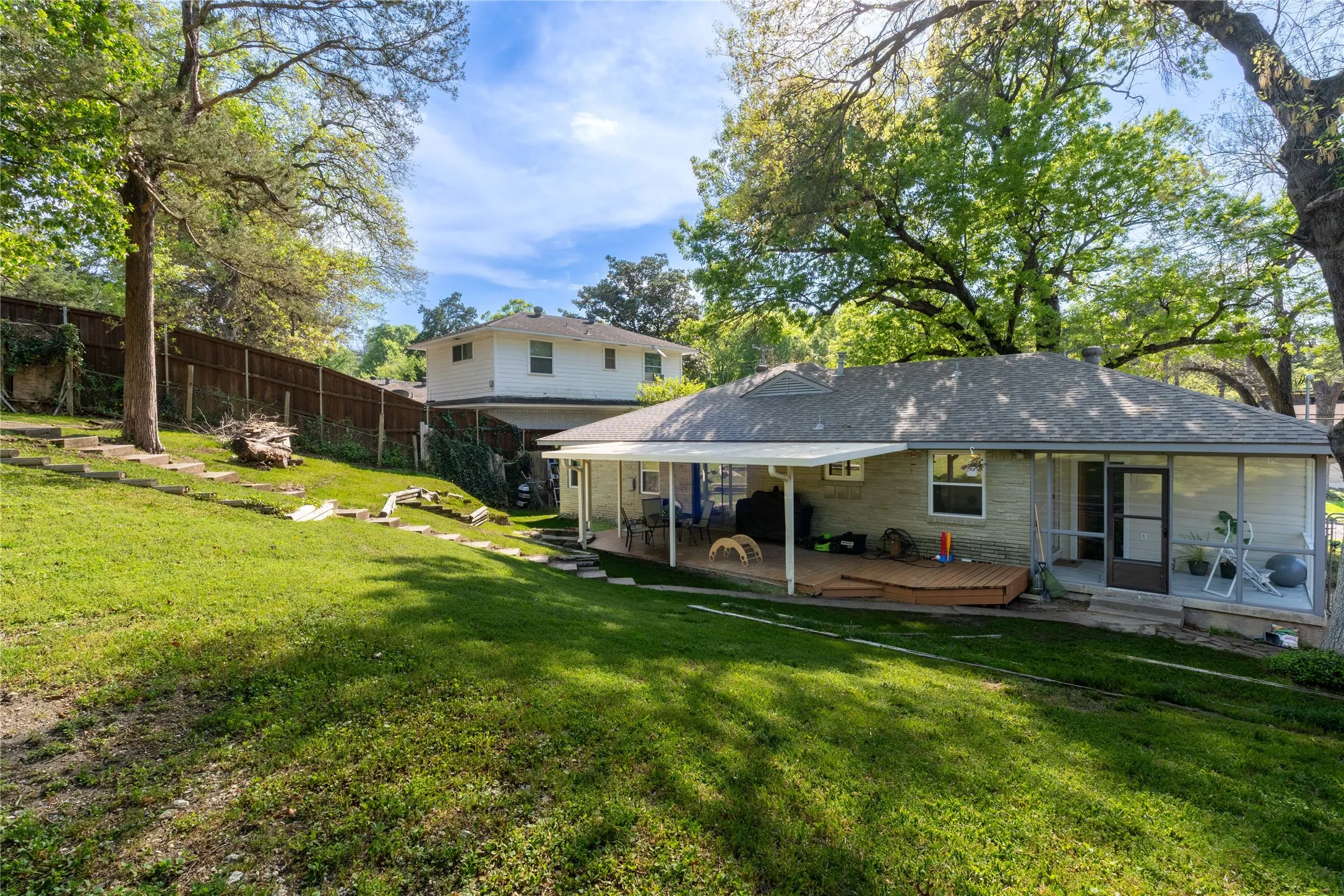 Back of house featuring a chimney, a deck, and a shingled roof