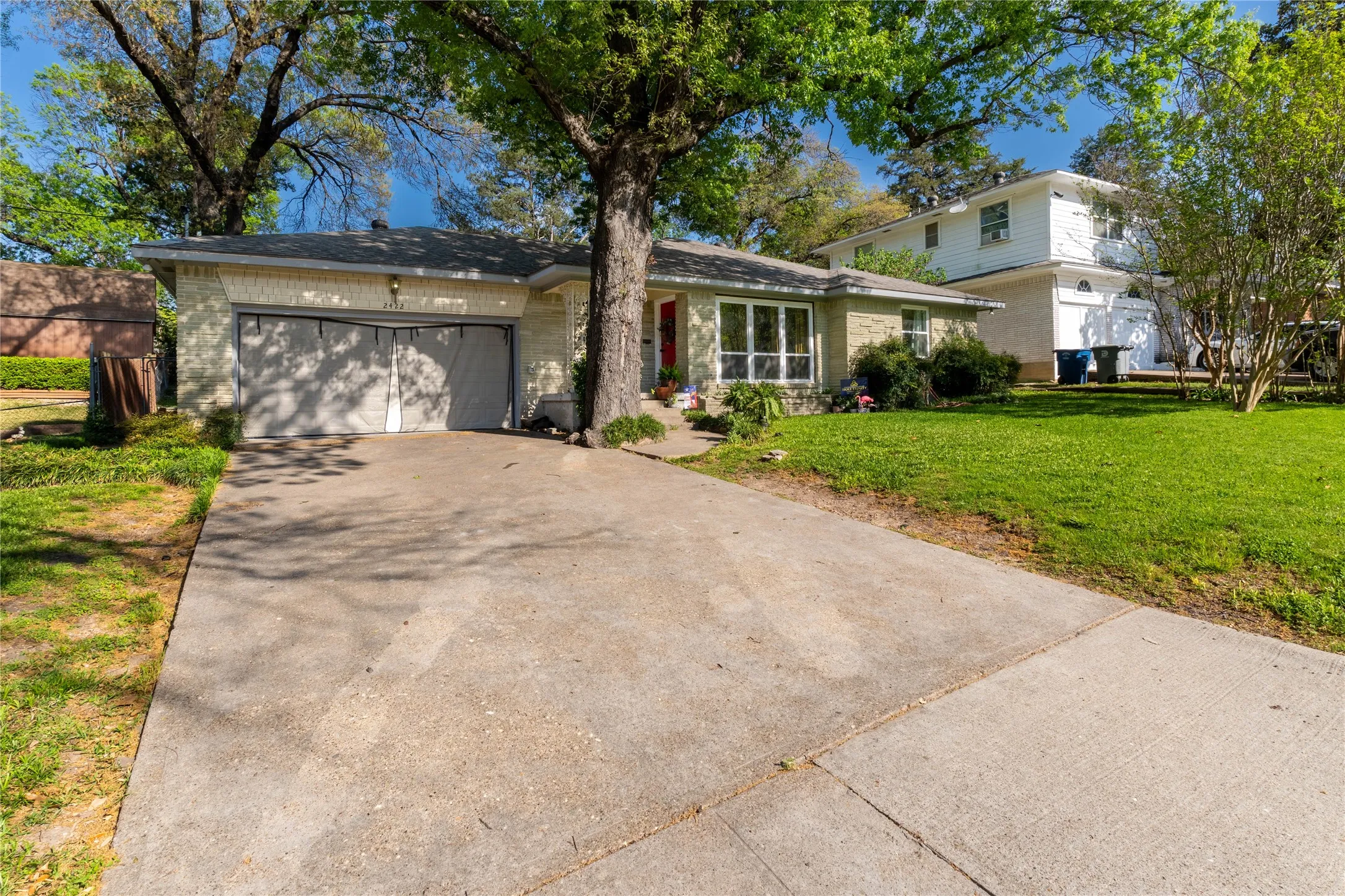 Traditional-style house featuring an attached garage, concrete driveway, a front yard, and brick siding