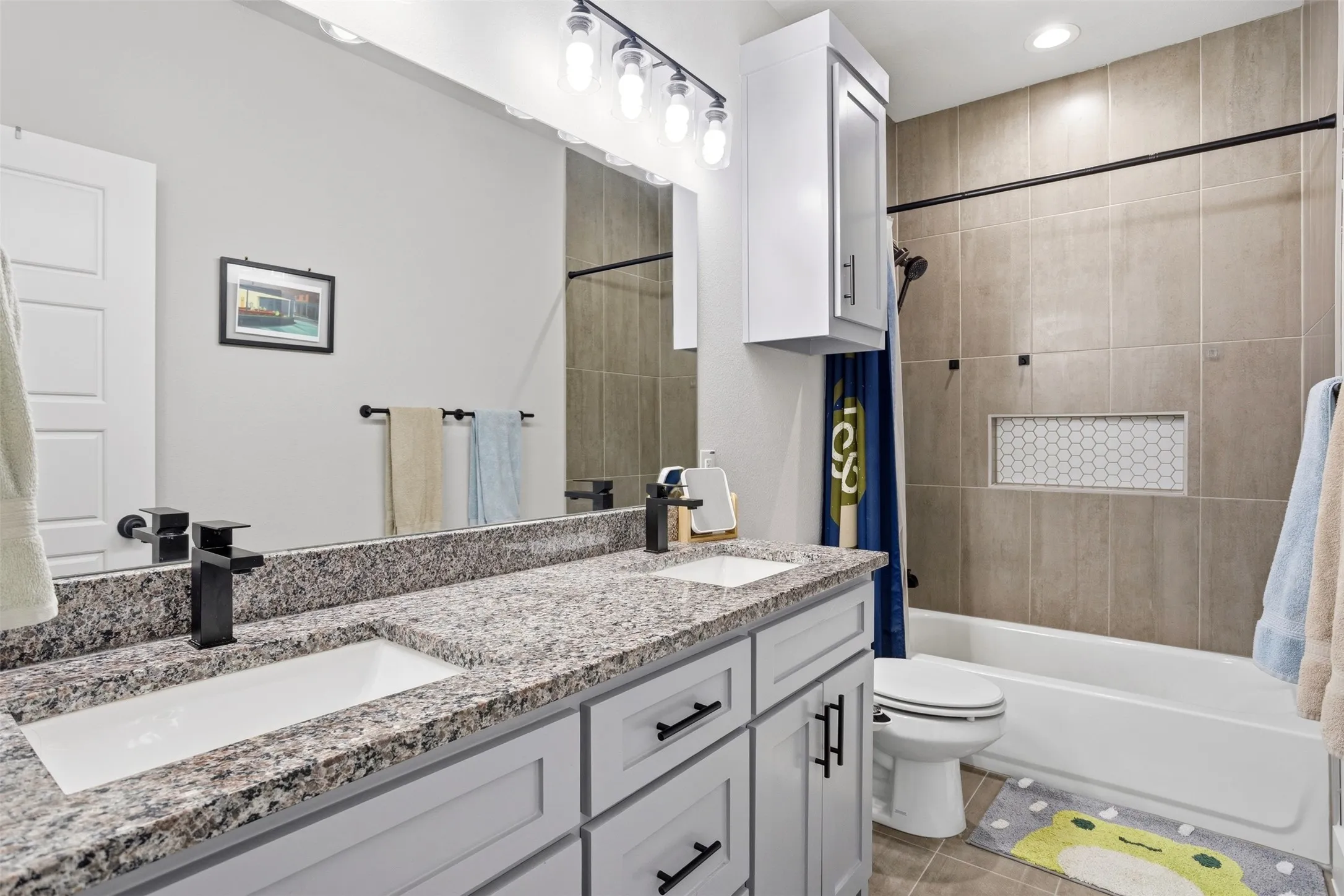 Full bathroom with double vanity, shower / tub combo with curtain, light tile patterned floors, and recessed lighting