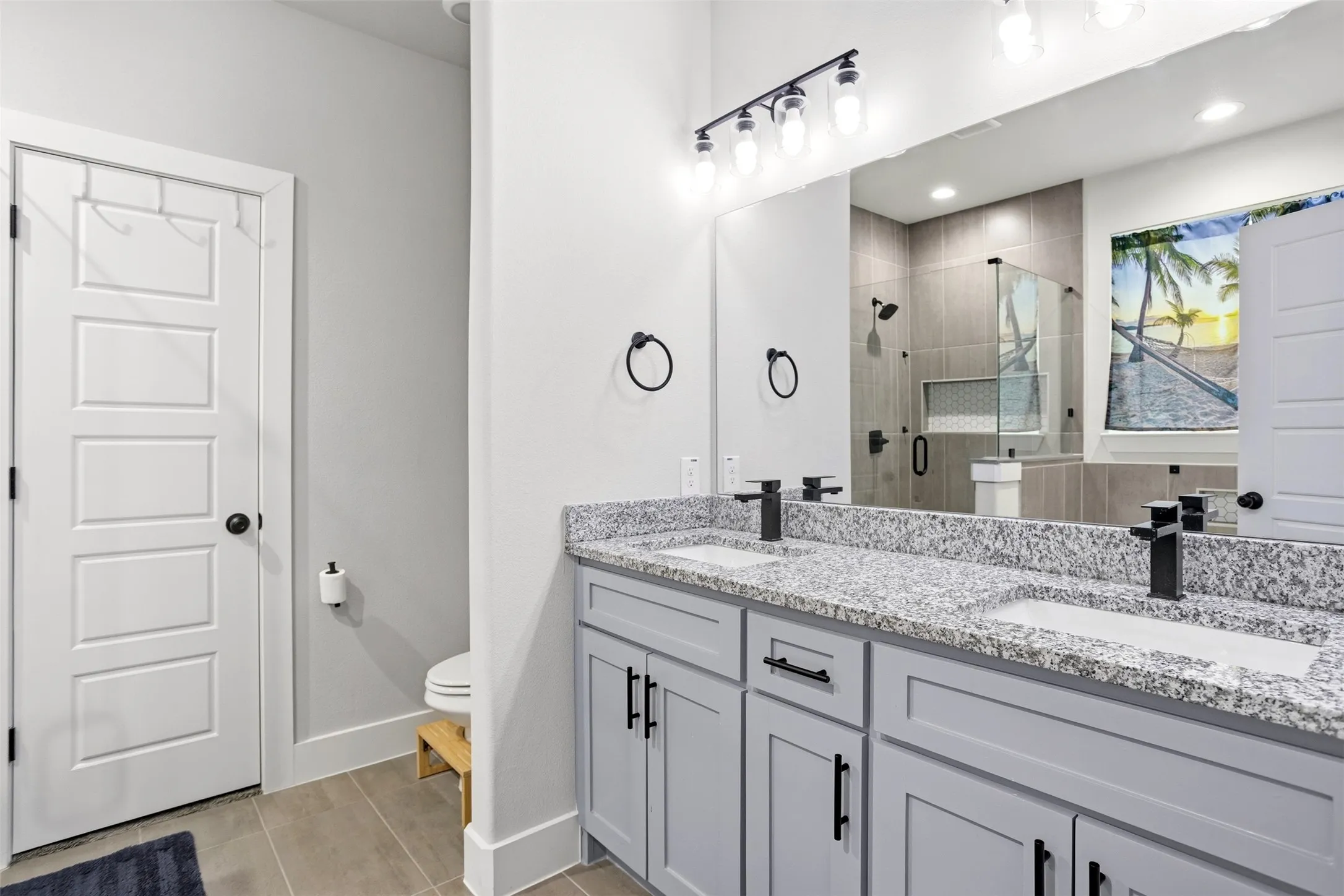 Full bath with double vanity, a stall shower, and light tile patterned flooring