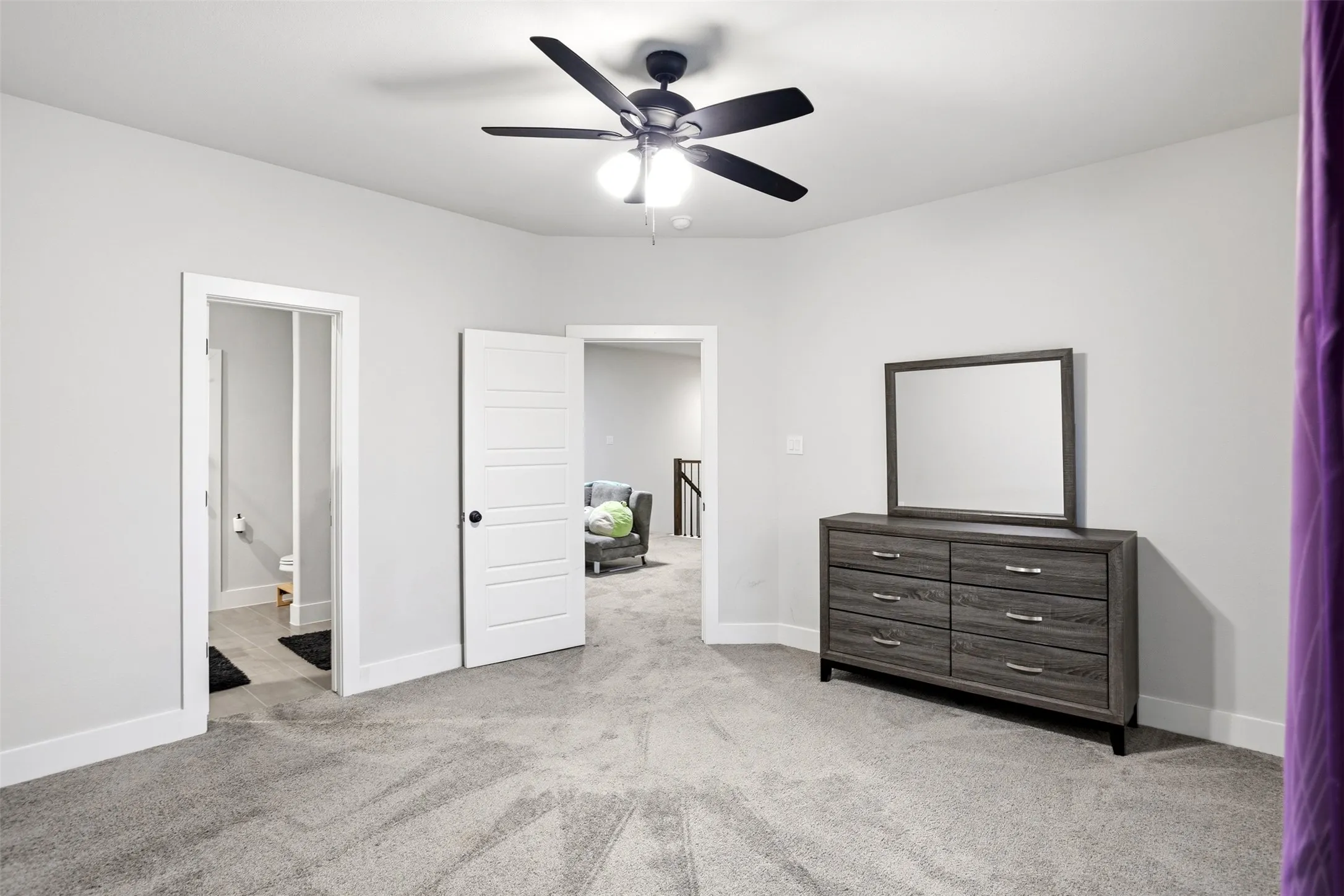 Unfurnished bedroom featuring light carpet, a ceiling fan, and ensuite bath