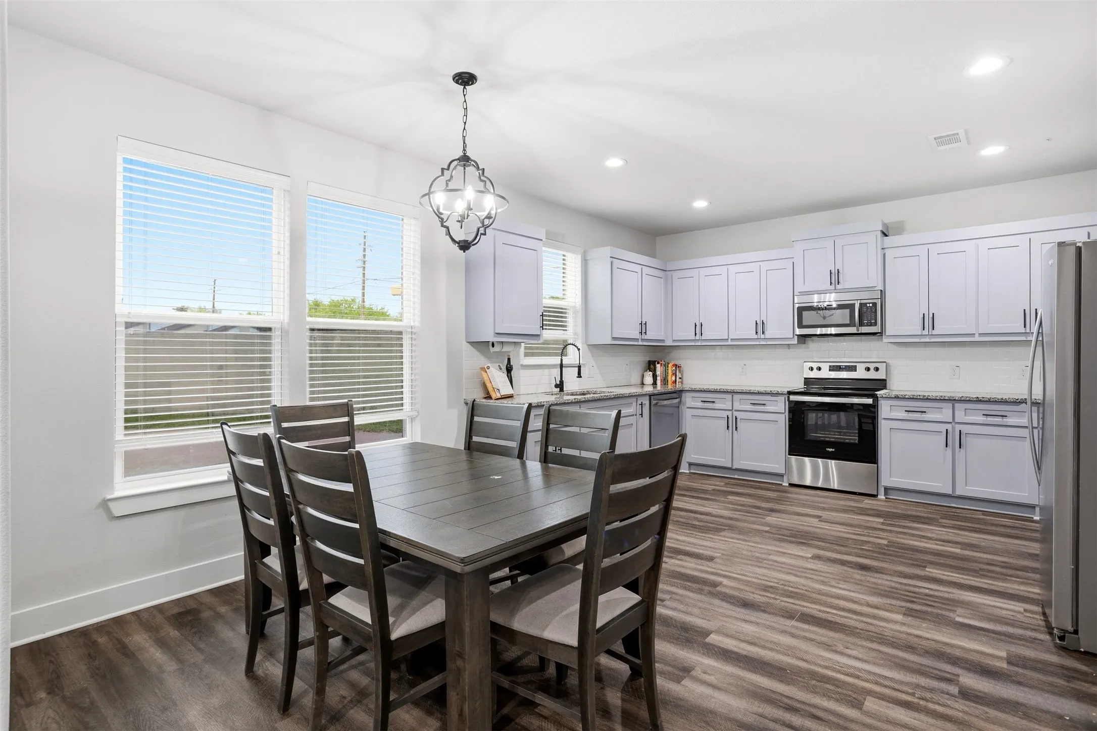 Dining area with dark wood-type flooring and hanging lights