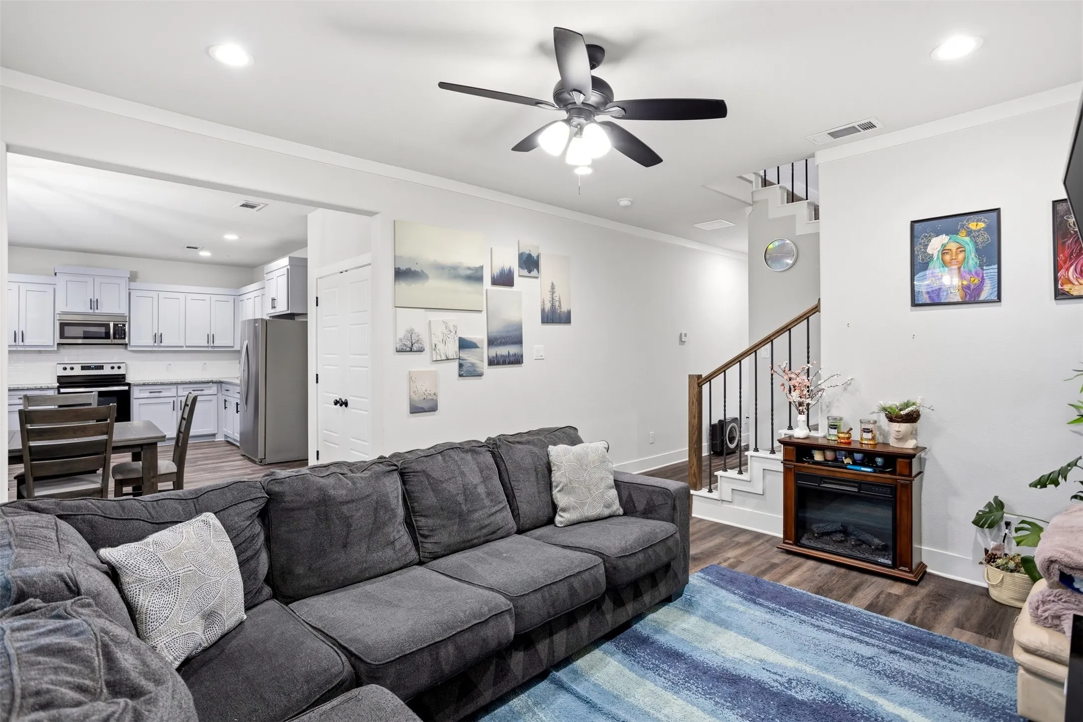 Living area with dark wood-type flooring, ceiling fan, recessed lighting, and ornamental molding