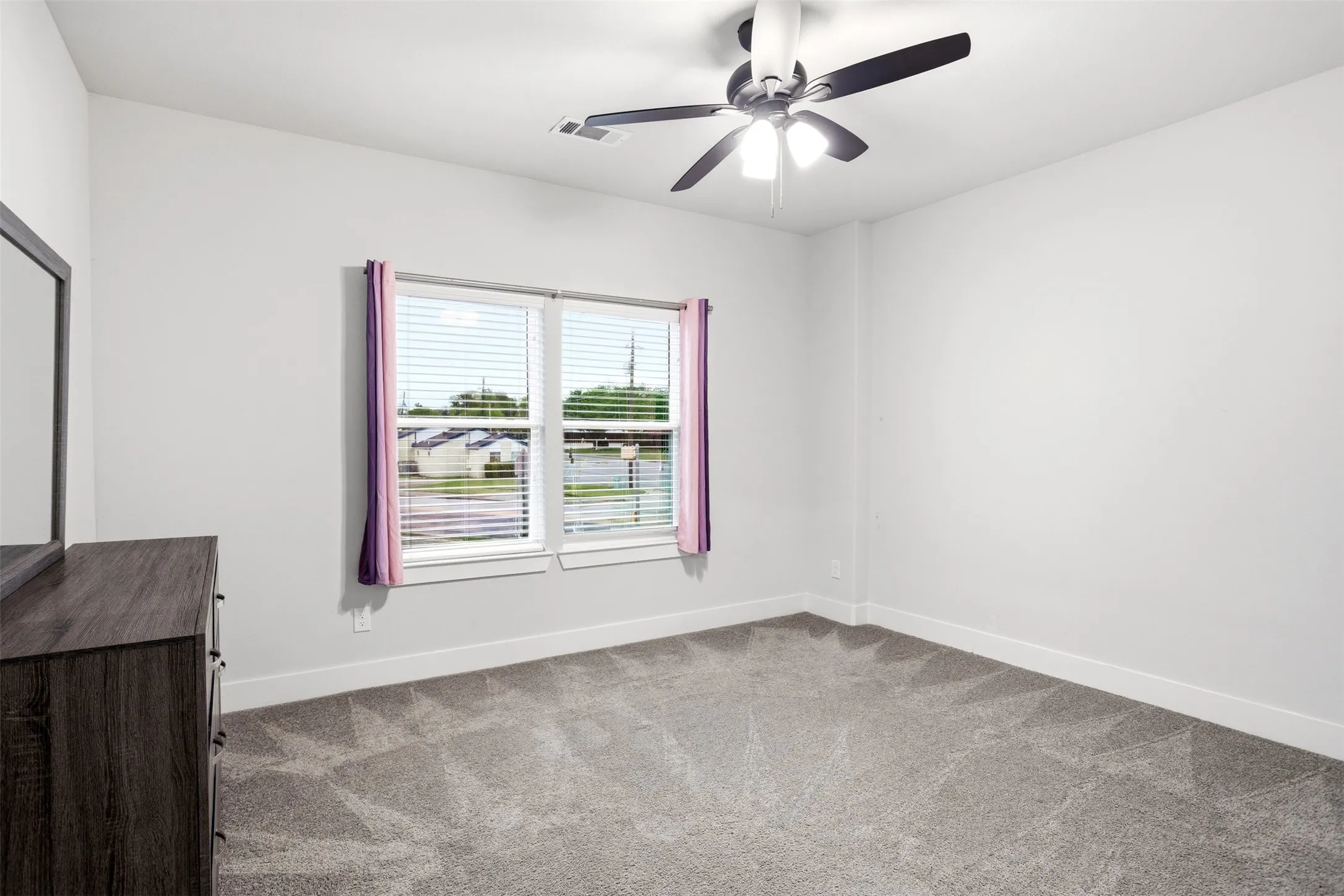 Empty room with light colored carpet and a ceiling fan