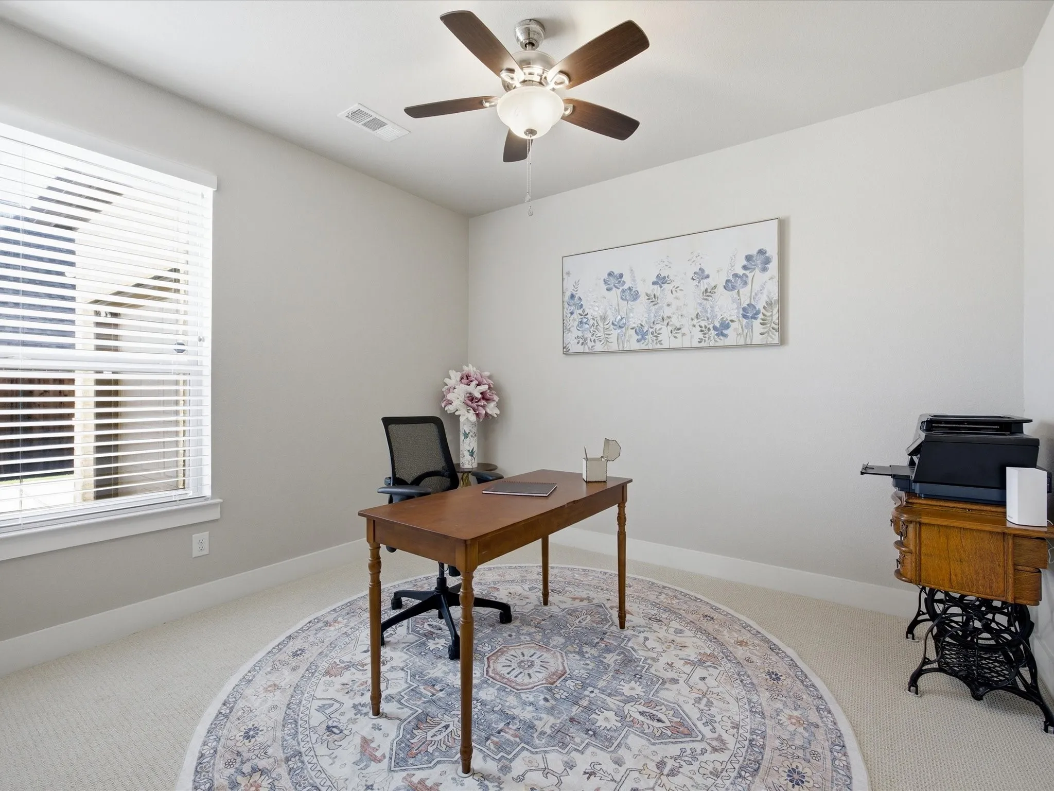 Office area featuring a ceiling fan and light carpet