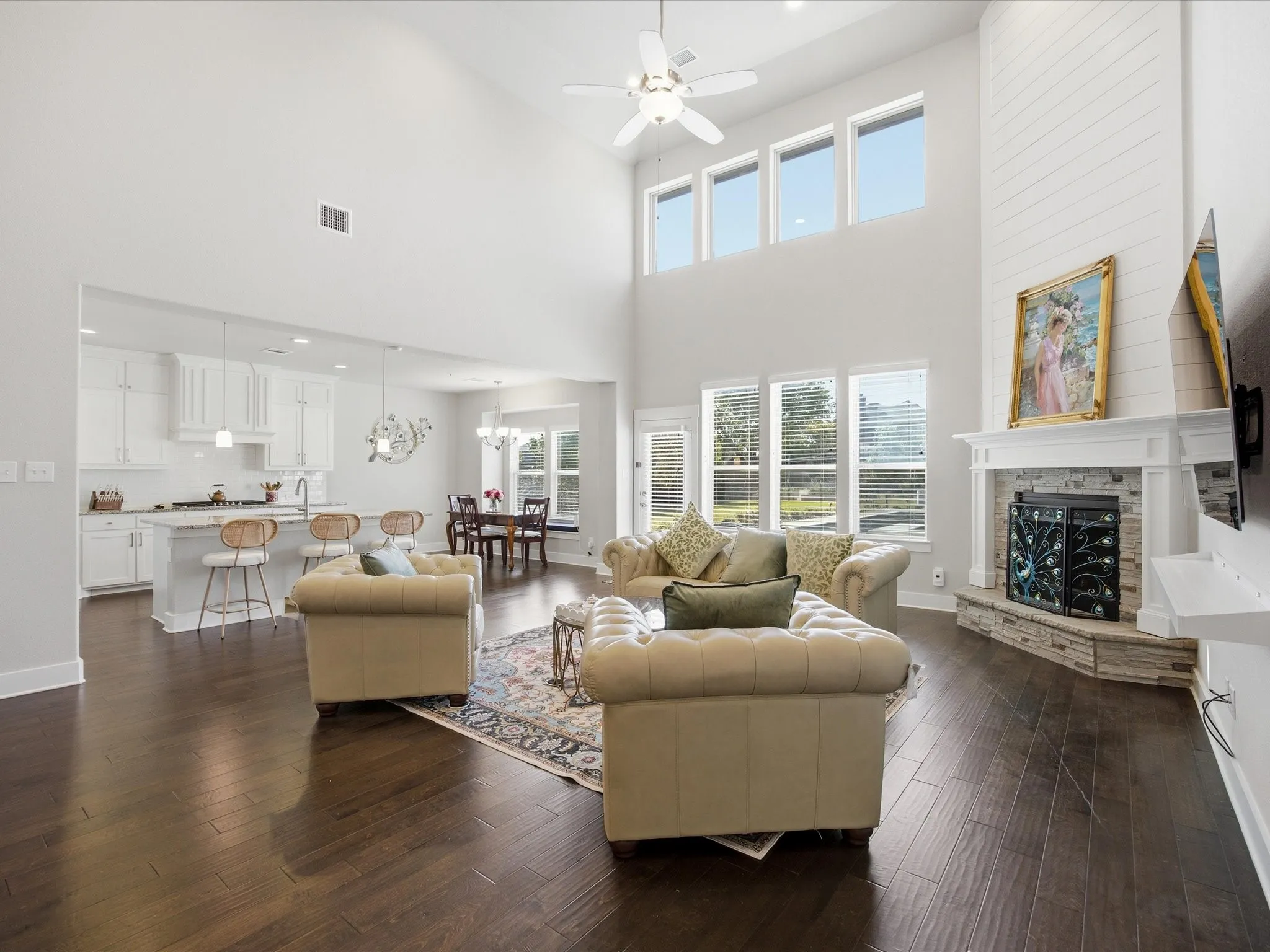 Living area featuring dark wood-style flooring, a ceiling fan, a fireplace, a high ceiling, and suspended lighting