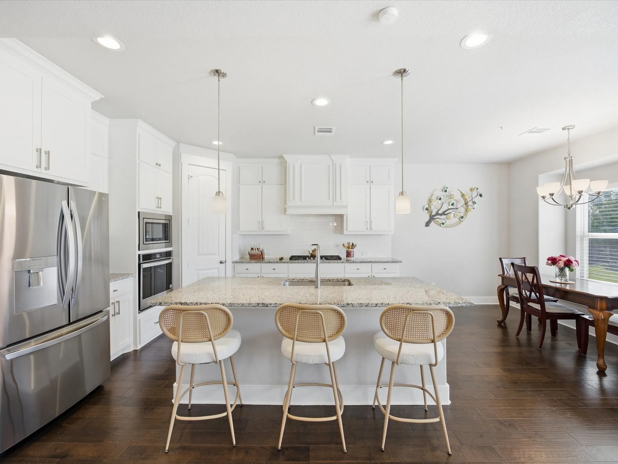 Kitchen featuring stainless steel appliances, light stone countertops, white cabinetry, and a center island with sink