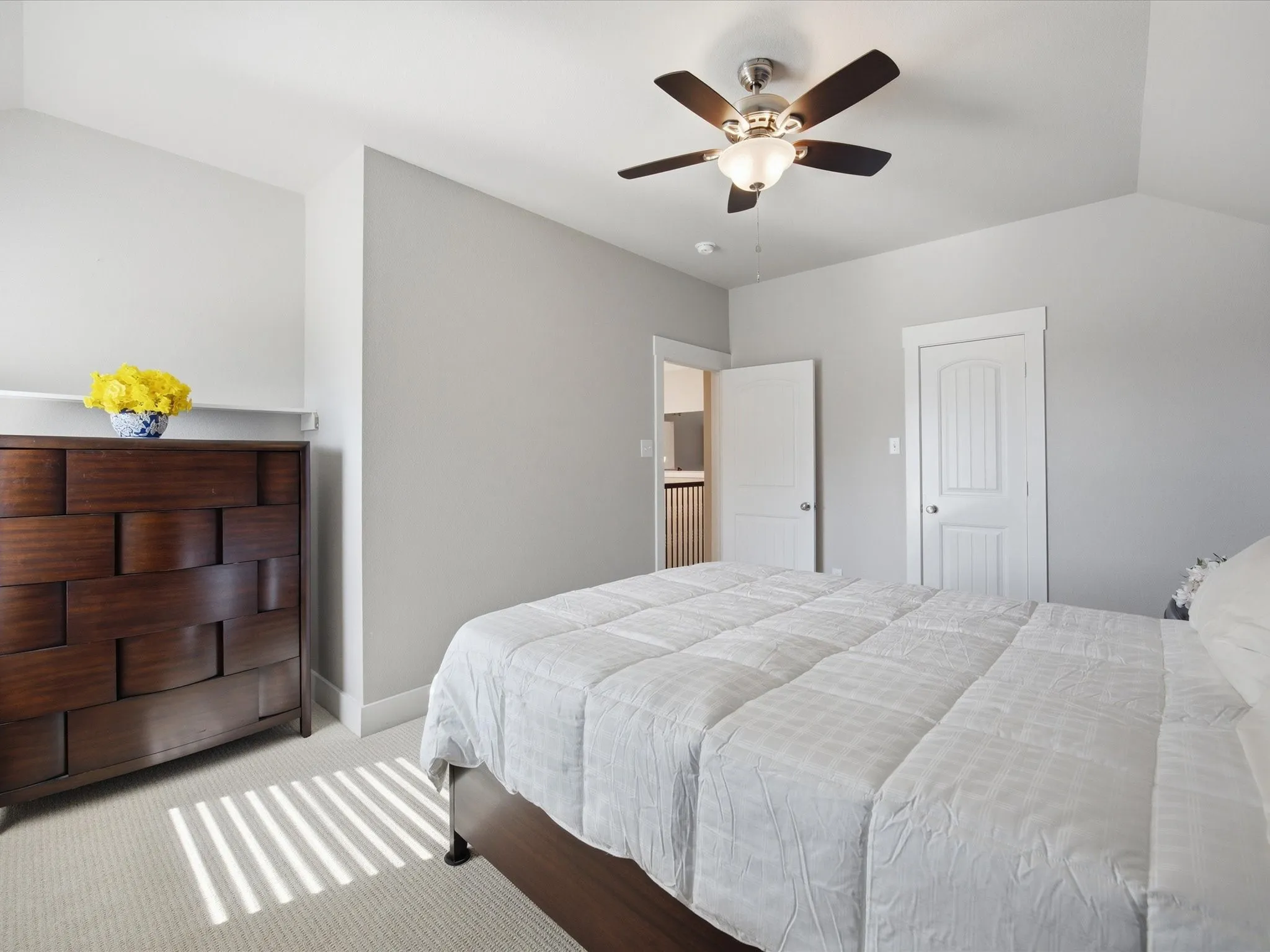 Bedroom with a ceiling fan, light colored carpet, and vaulted ceiling