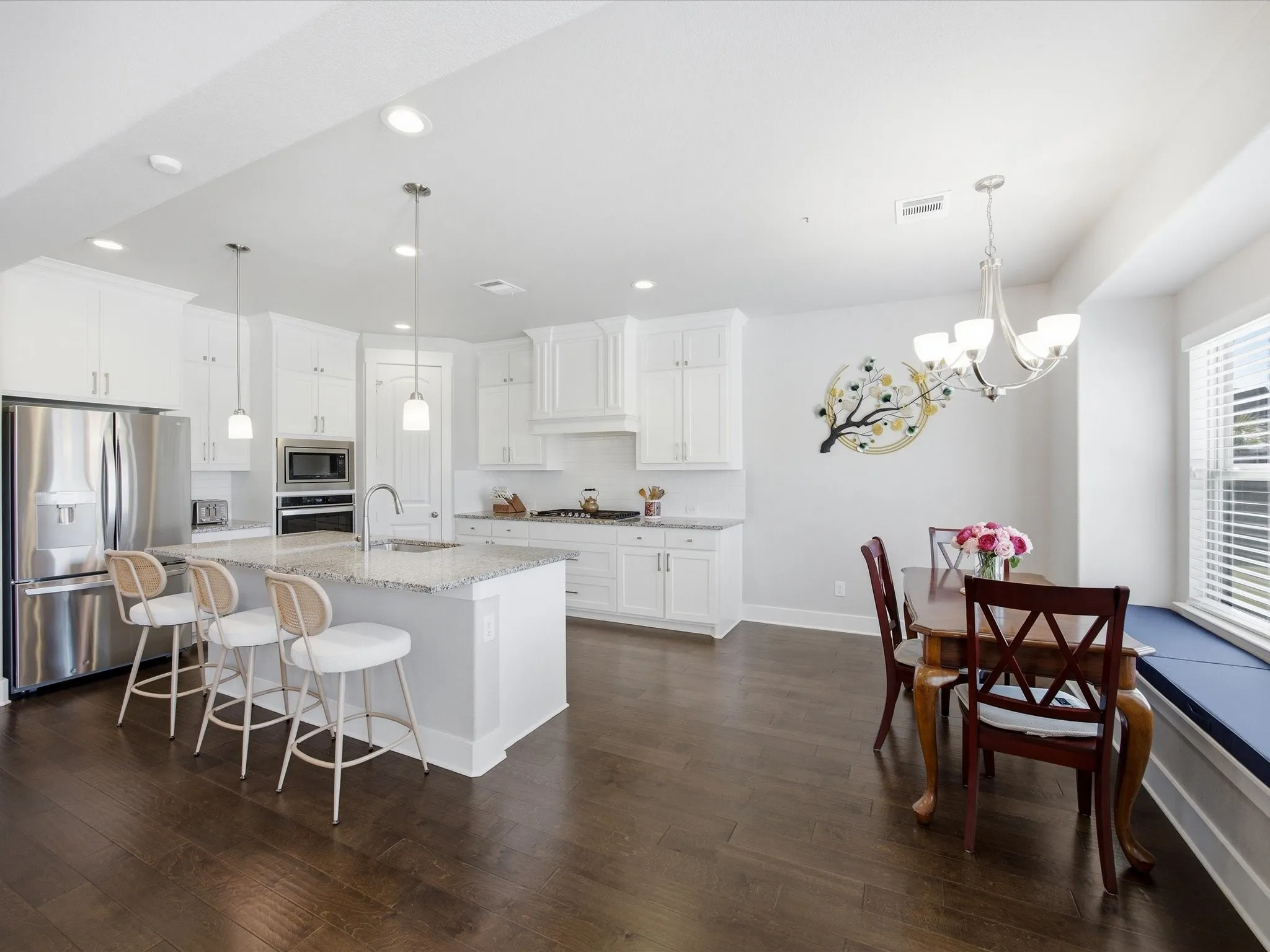 Kitchen featuring stainless steel appliances, light stone countertops, white cabinetry, and a kitchen breakfast bar