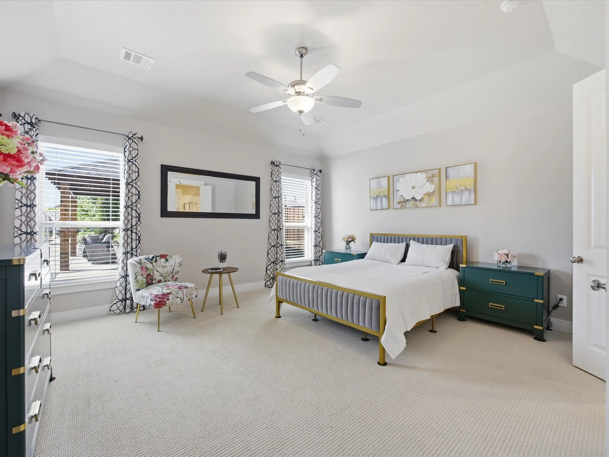 Primary bedroom with multiple windows, light colored carpet, and ceiling fan
