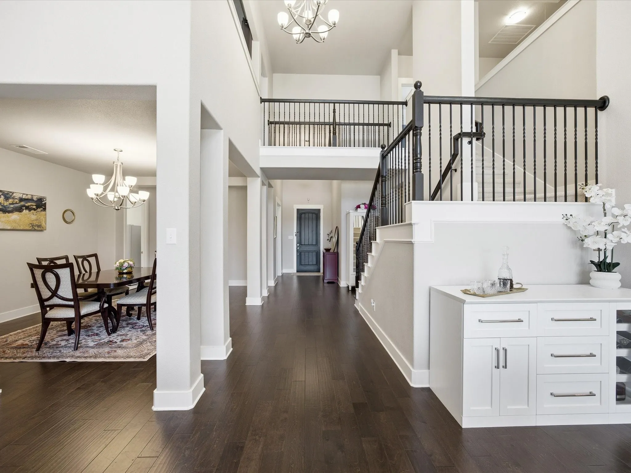Entrance foyer with hanging lights, a high ceiling, and dark wood-type flooring