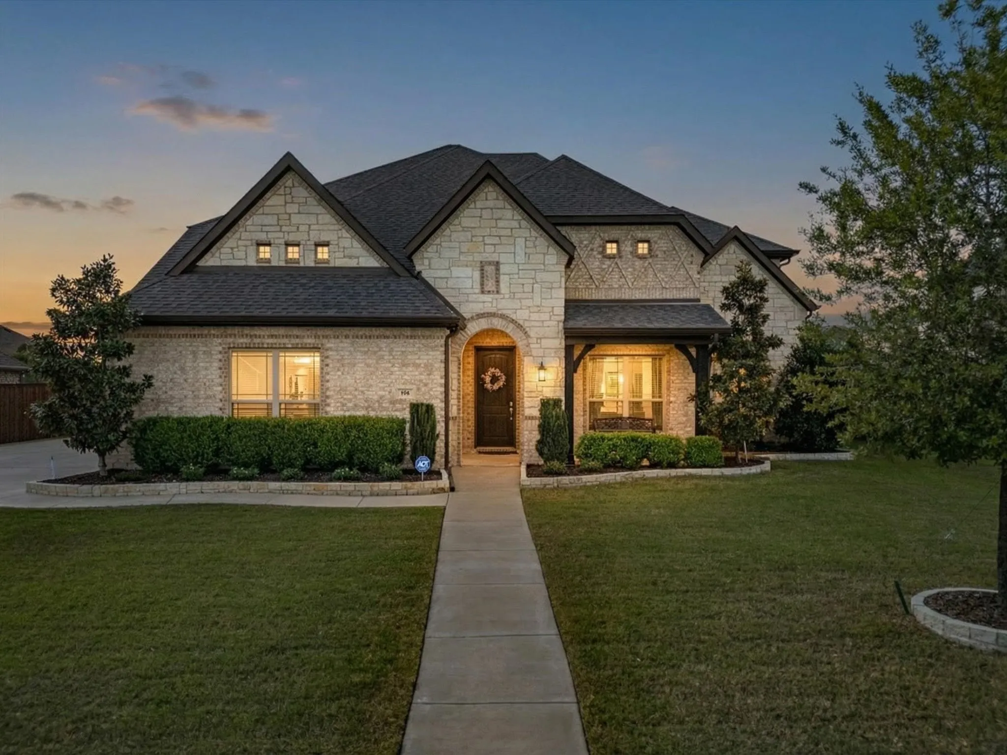 French country style house featuring a lawn, stone siding, brick siding, roof with shingles, and a porch