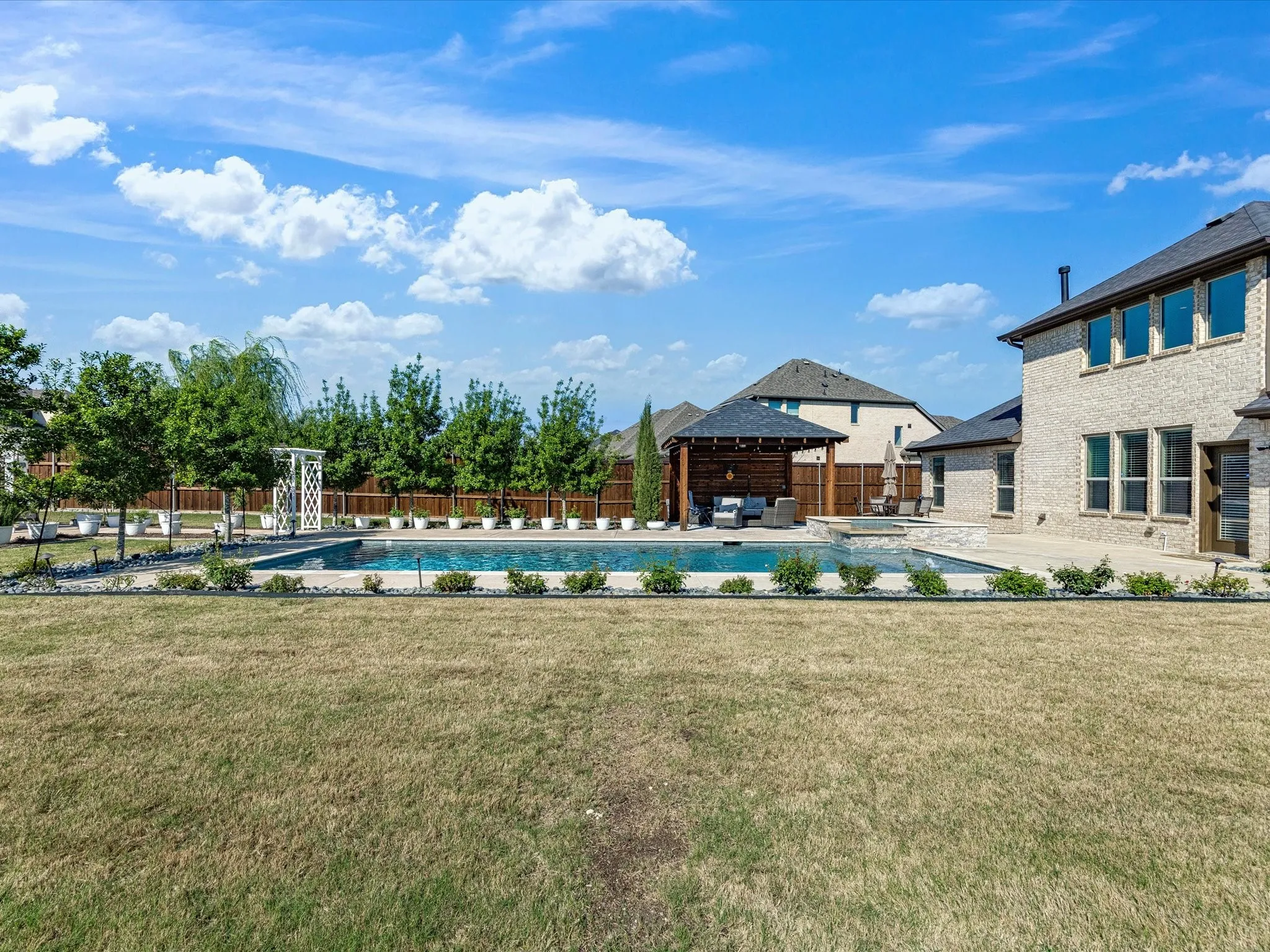 Community pool with a patio area and a fenced backyard