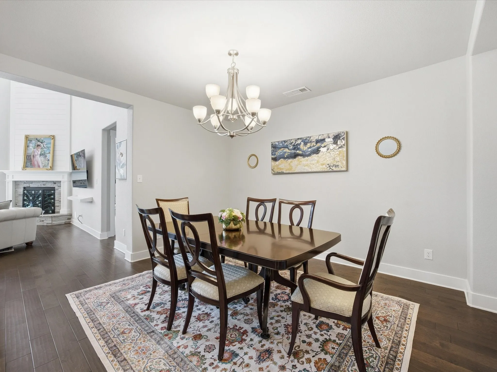 Dining room with hanging lights, dark wood-style flooring, and a fireplace with raised hearth