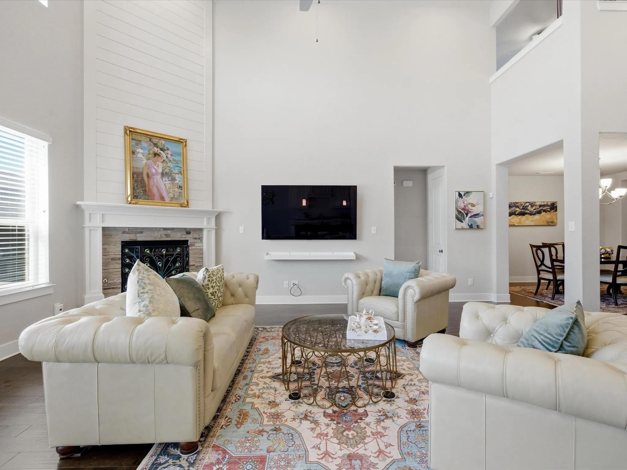 Living room with a high ceiling, wood finished floors, ceiling fan, a premium fireplace, and hanging lights
