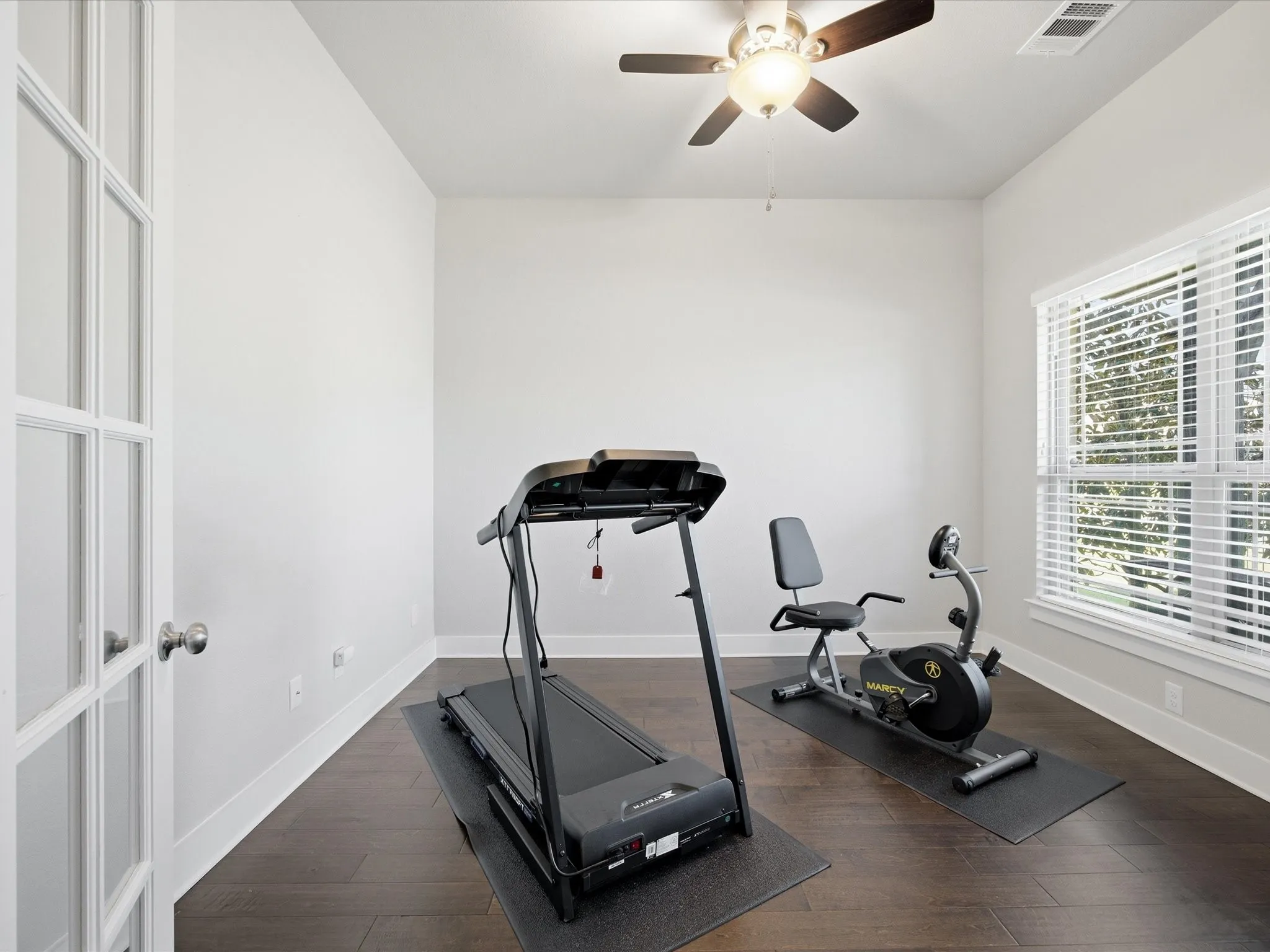 Exercise room featuring dark wood-type flooring and ceiling fan