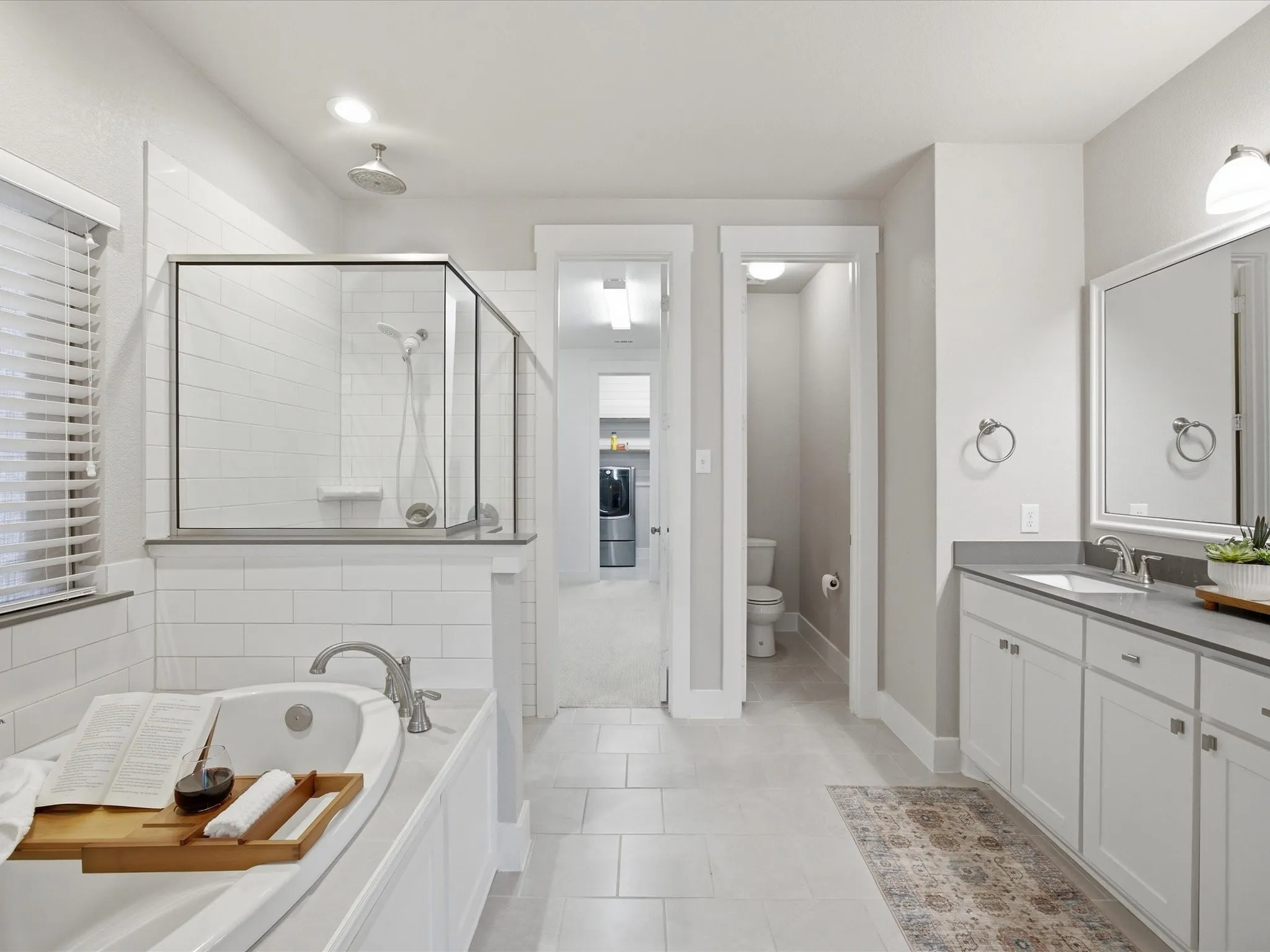 Bathroom featuring vanity, a stall shower, a garden tub, light tile patterned floors, and washer / clothes dryer