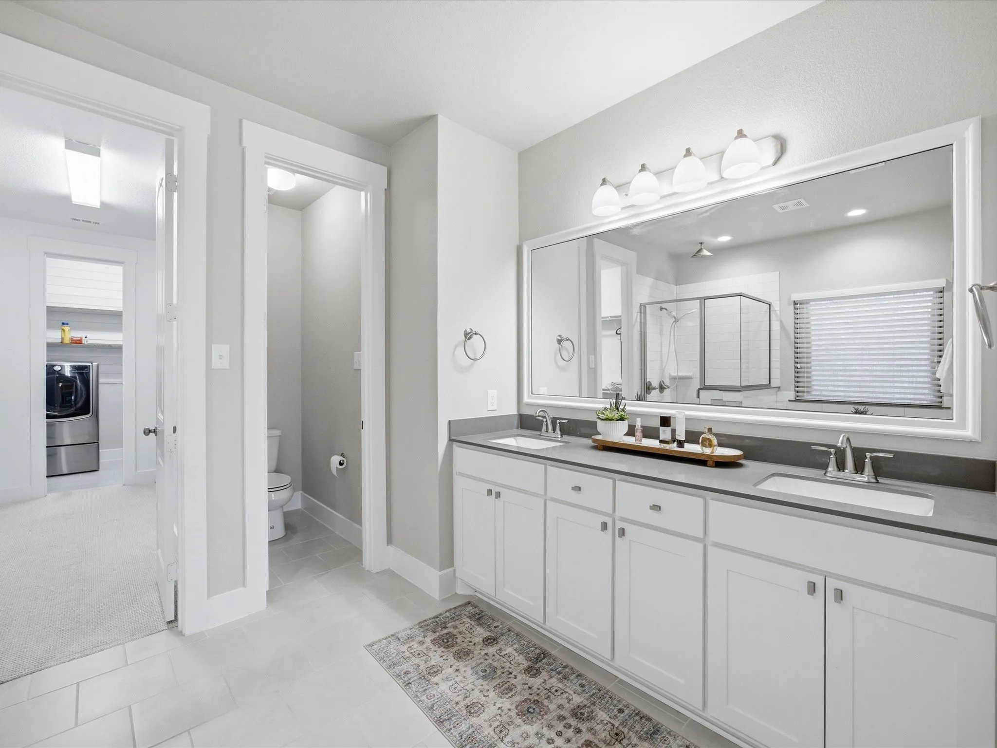 Bathroom featuring double vanity, washer / dryer, a shower stall, and light carpet