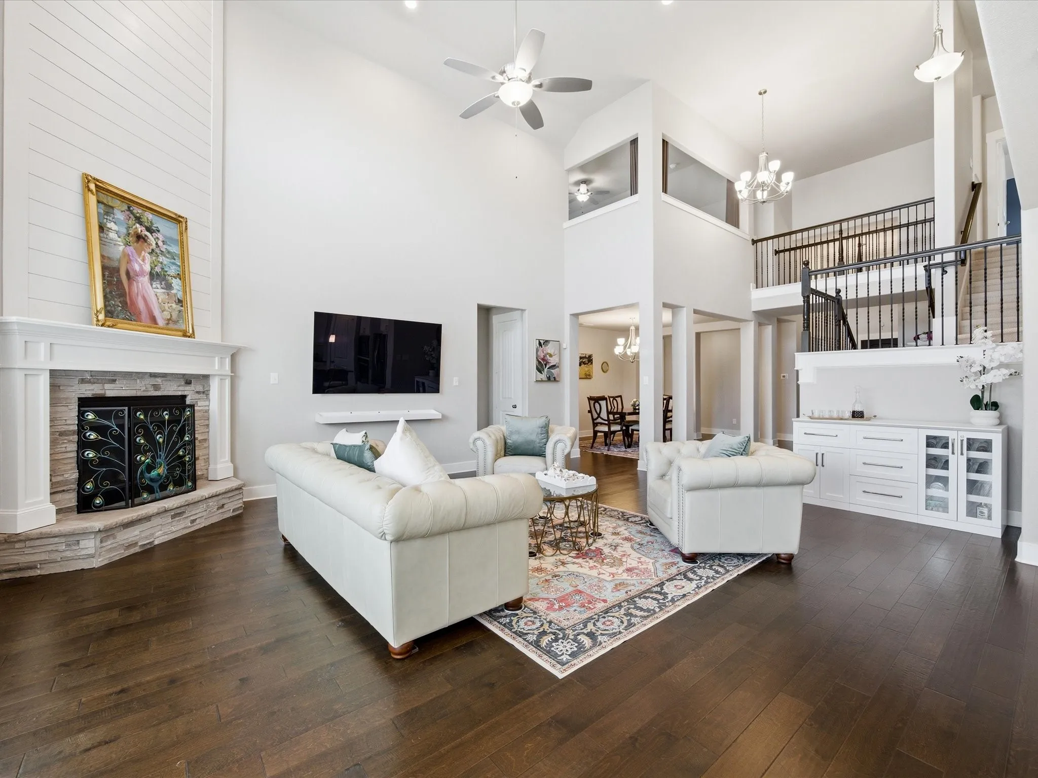 Living area featuring a chandelier, dark wood-type flooring, a ceiling fan, a high ceiling, and a fireplace