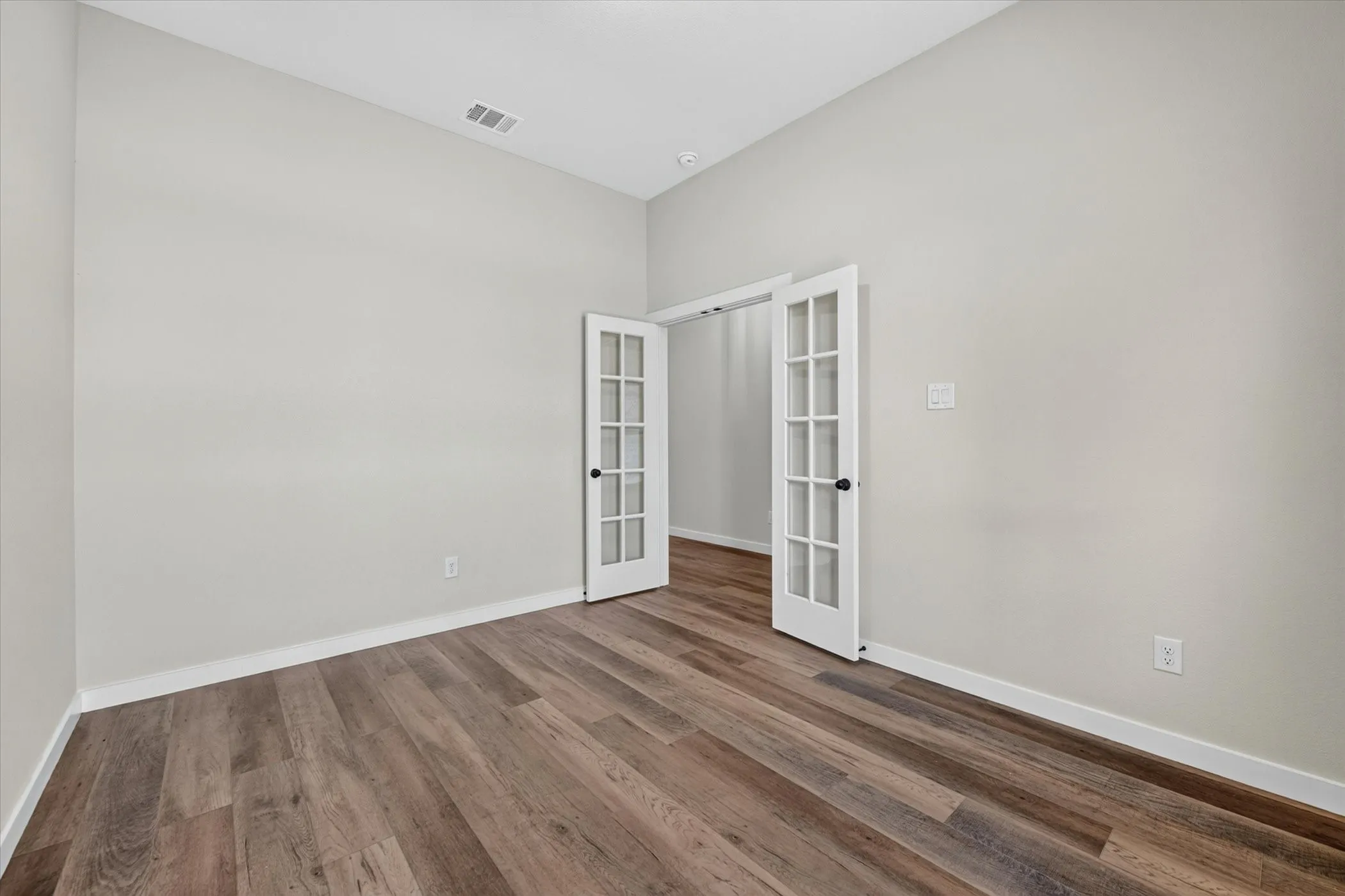 Room featuring wood-finish flooring, light neutral wall paint, and white baseboards