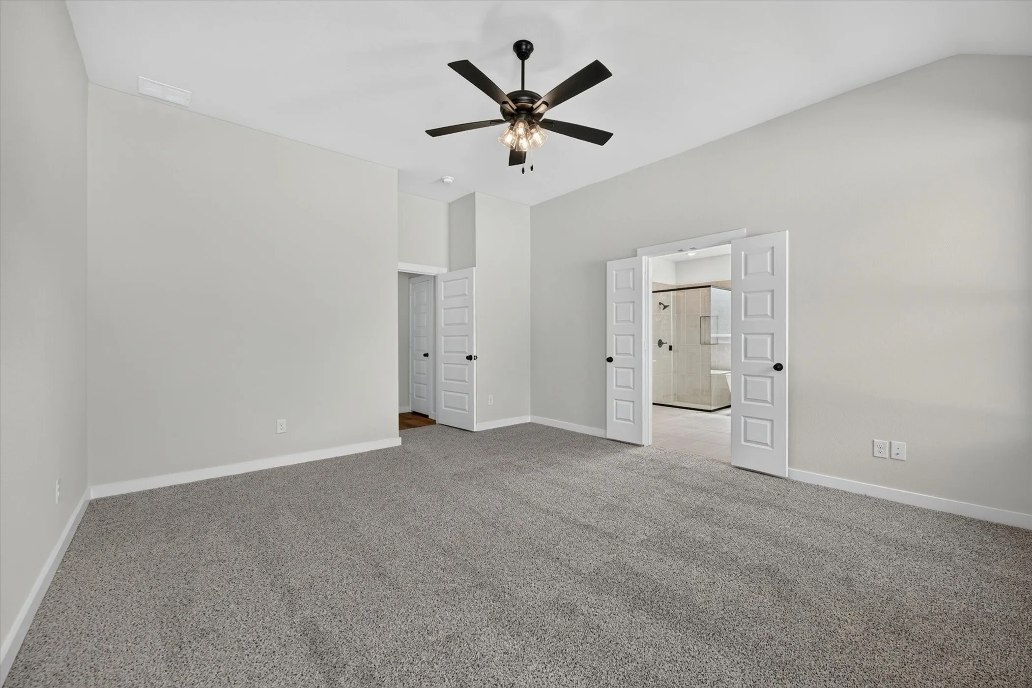 Spacious room featuring vaulted ceilings, light gray wall paint, and gray carpet flooring
