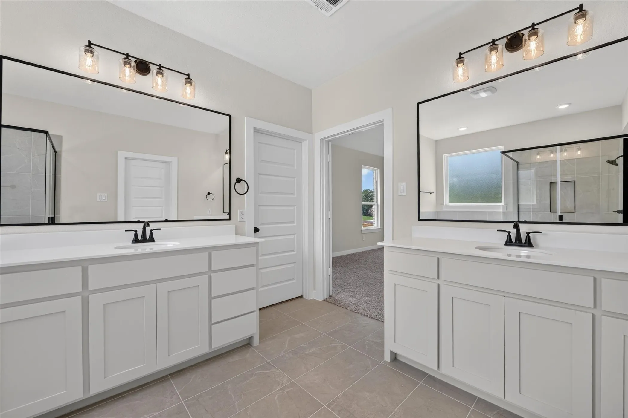 Bathroom featuring dual vanities with white cabinetry, white countertops, and black fixtures