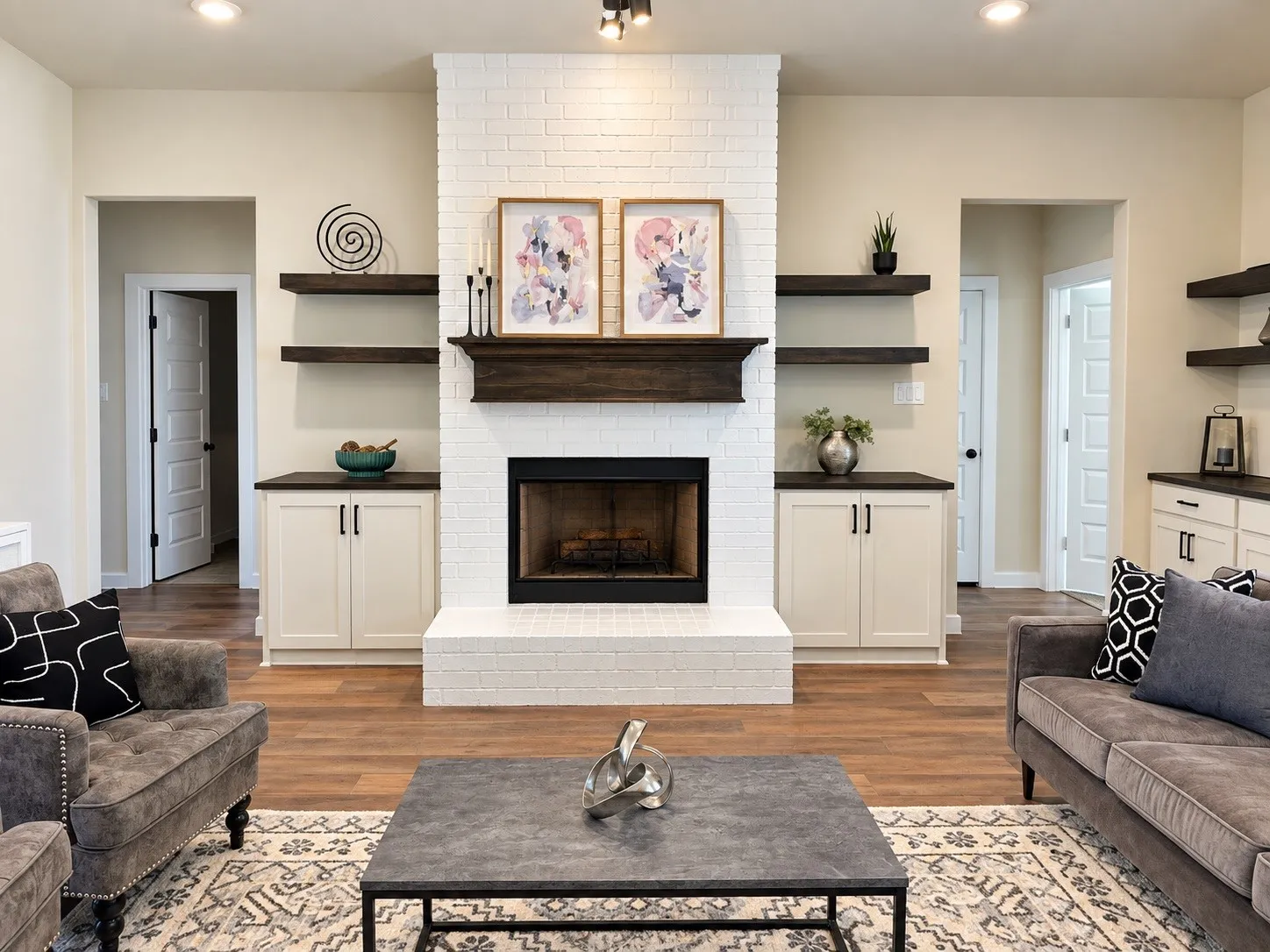 Wood-finish flooring throughout, complemented by a white brick fireplace with a dark mantel