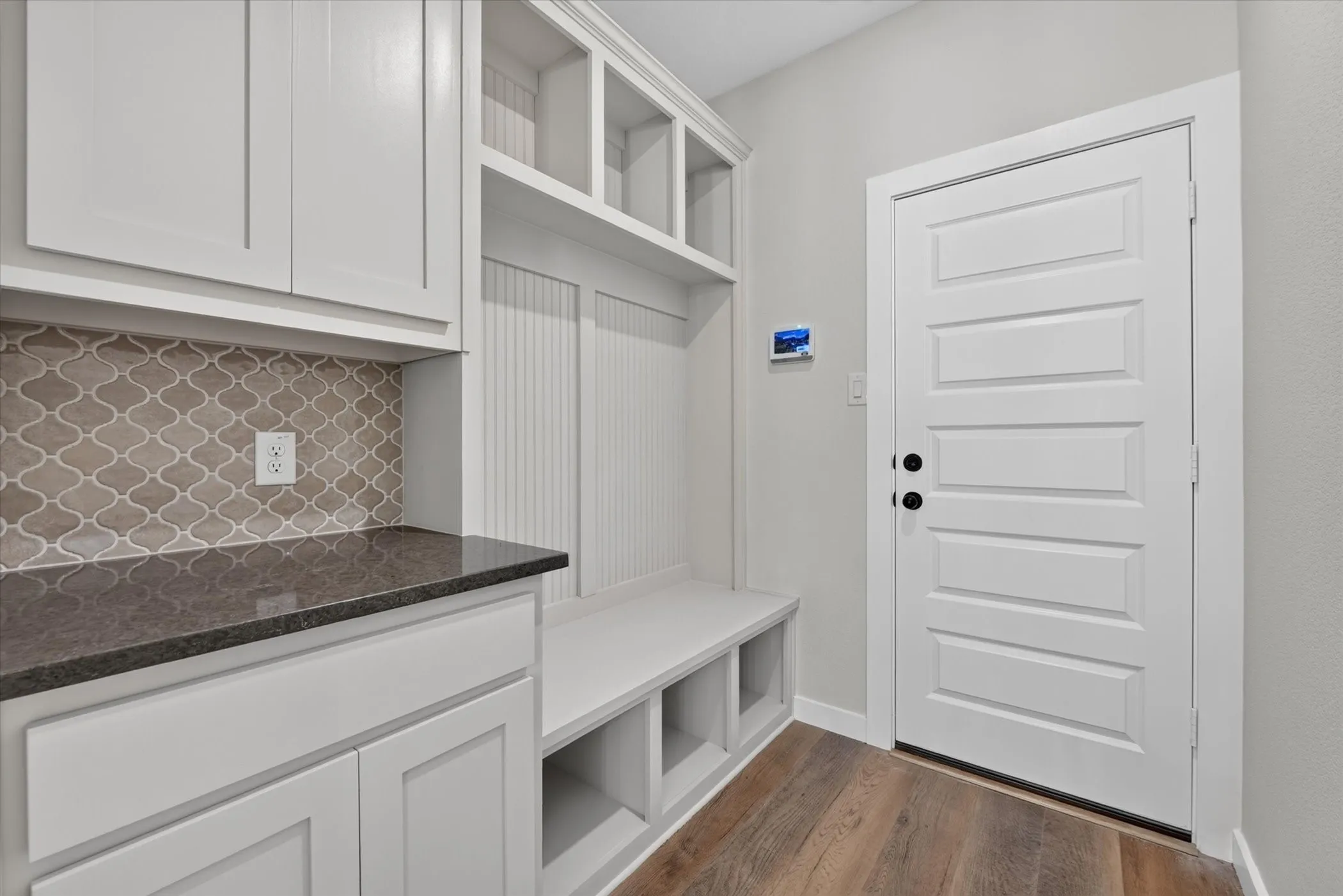 Built-in white cabinetry and shelving system featuring a wood-finish bench