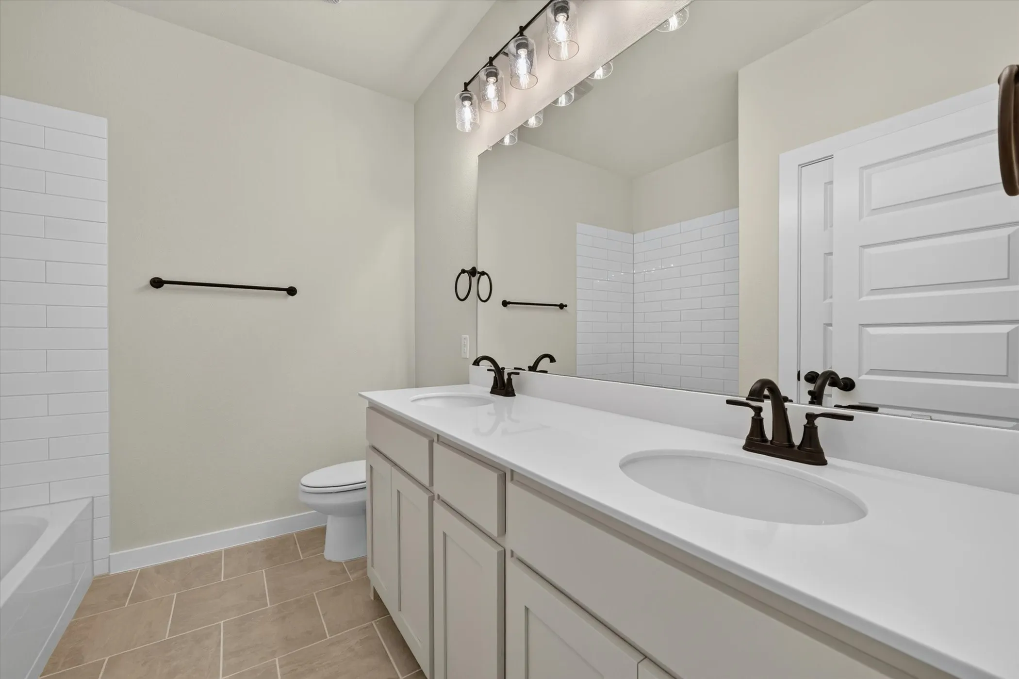 Bathroom featuring a dual vanity with white countertops, integrated sinks, and bronze-finish fixtures