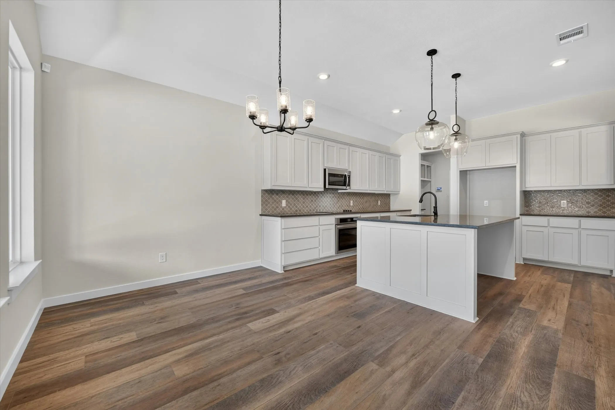 Open concept kitchen with a central island featuring a dark countertop and a matte black faucet