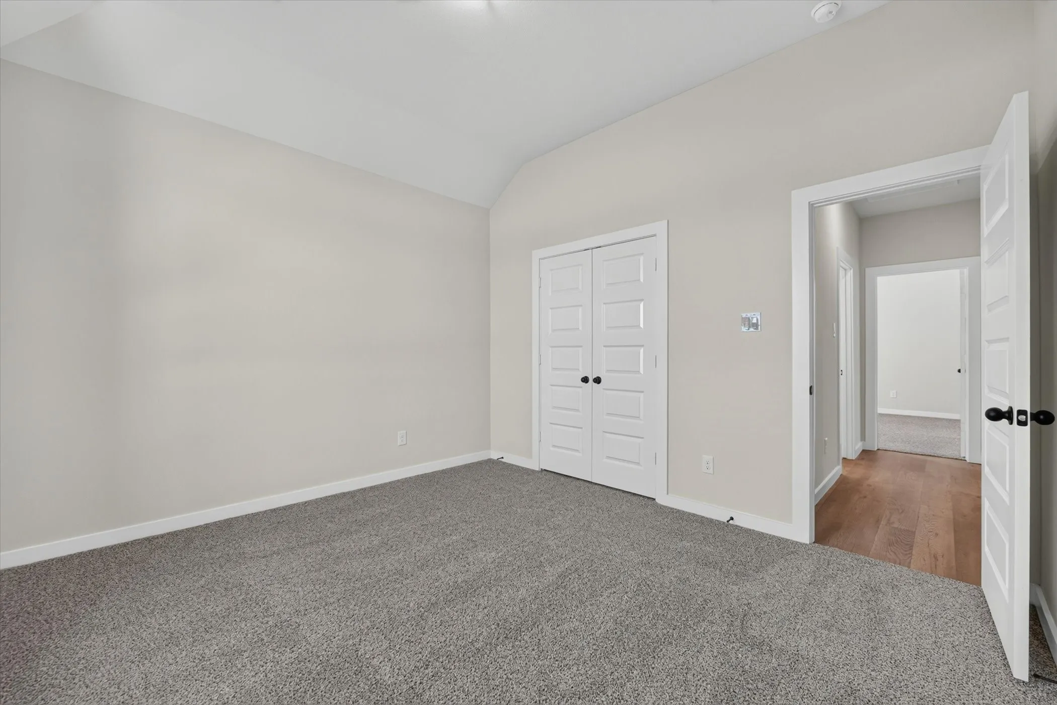 Vaulted ceiling room with grey carpeting and white trim