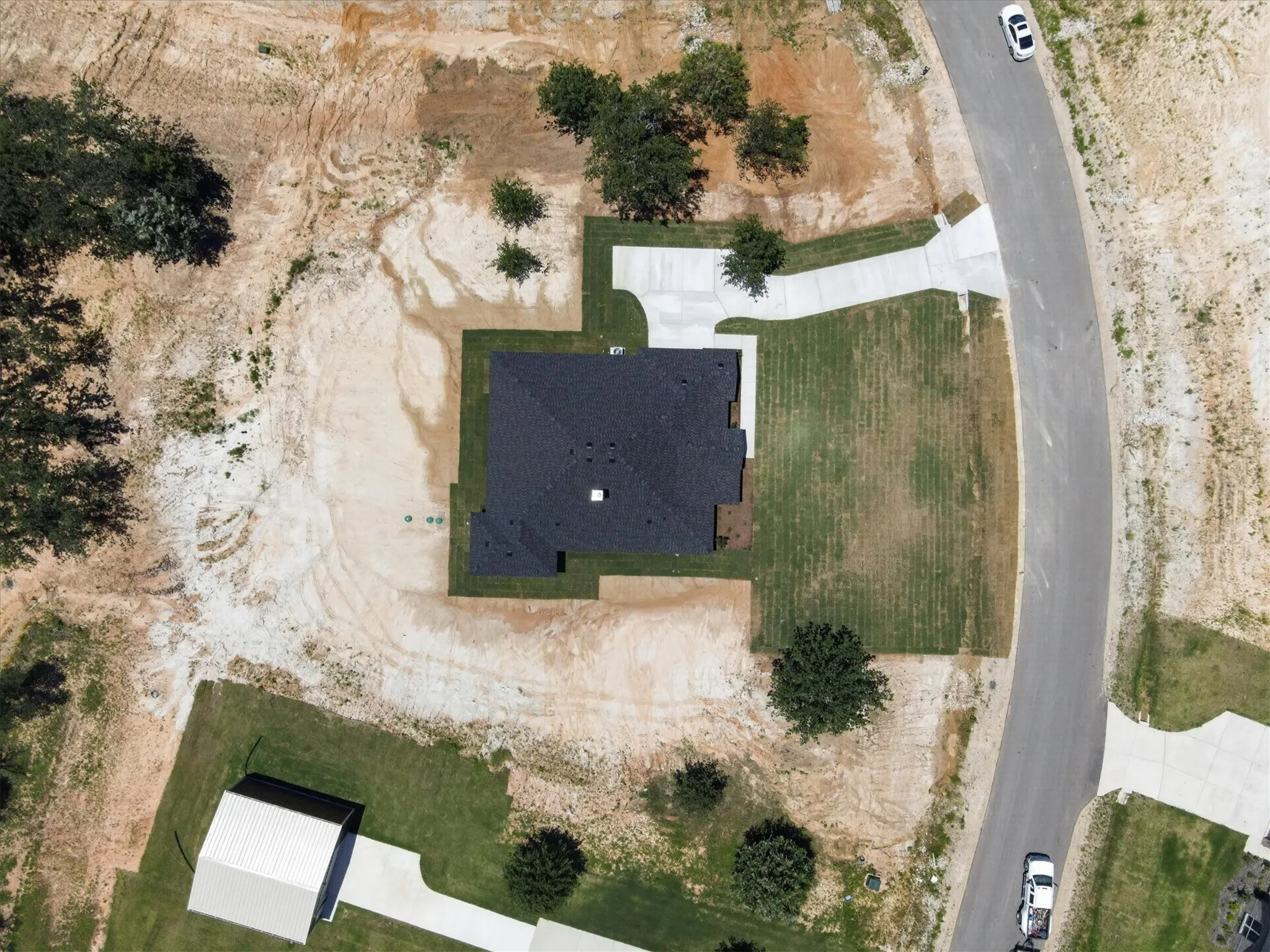 Newly constructed residence with a dark shingle roof, established lawn areas, and a concrete driveway