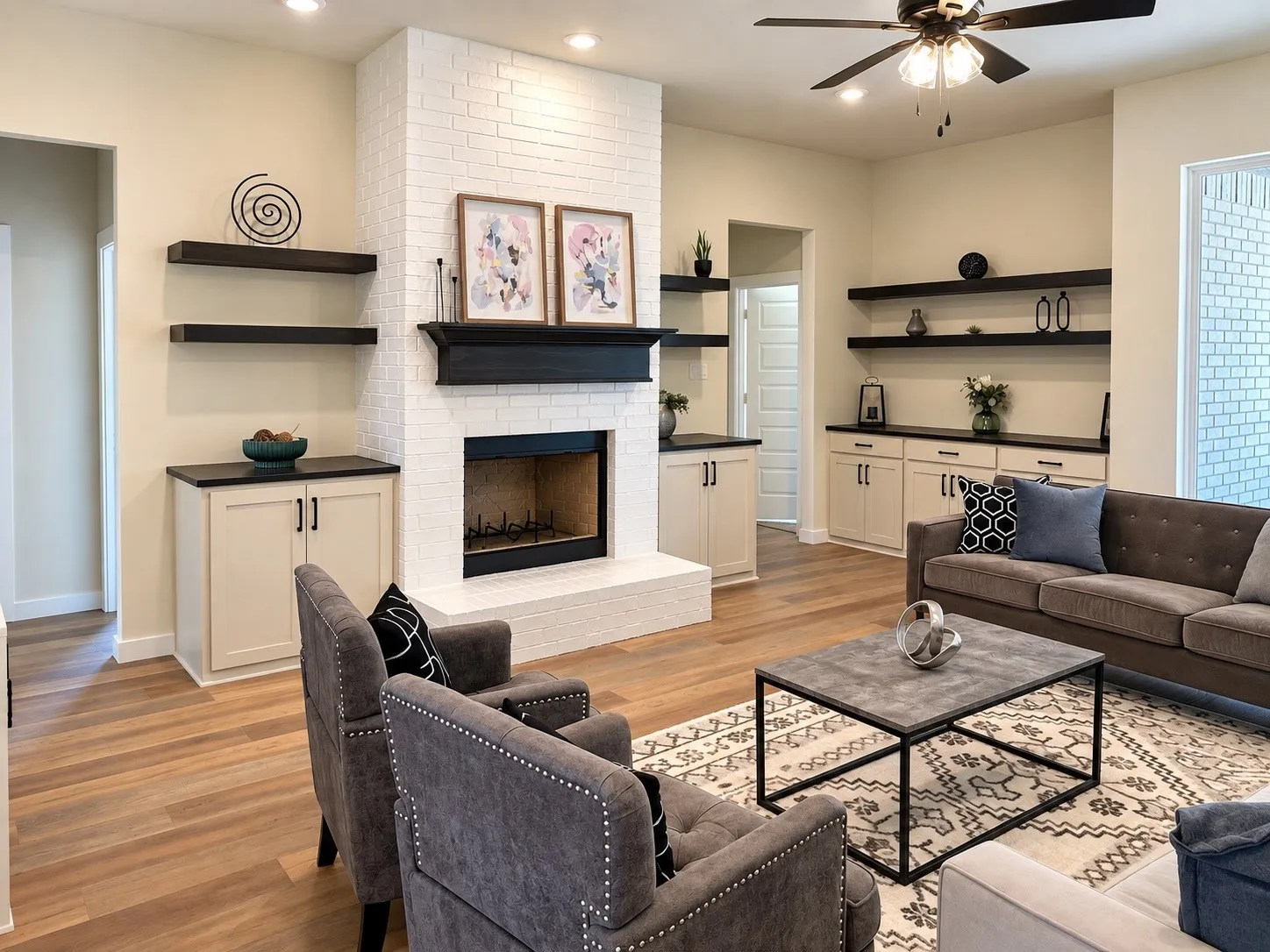 Wood-finish flooring throughout, complemented by a white brick fireplace with a dark mantel