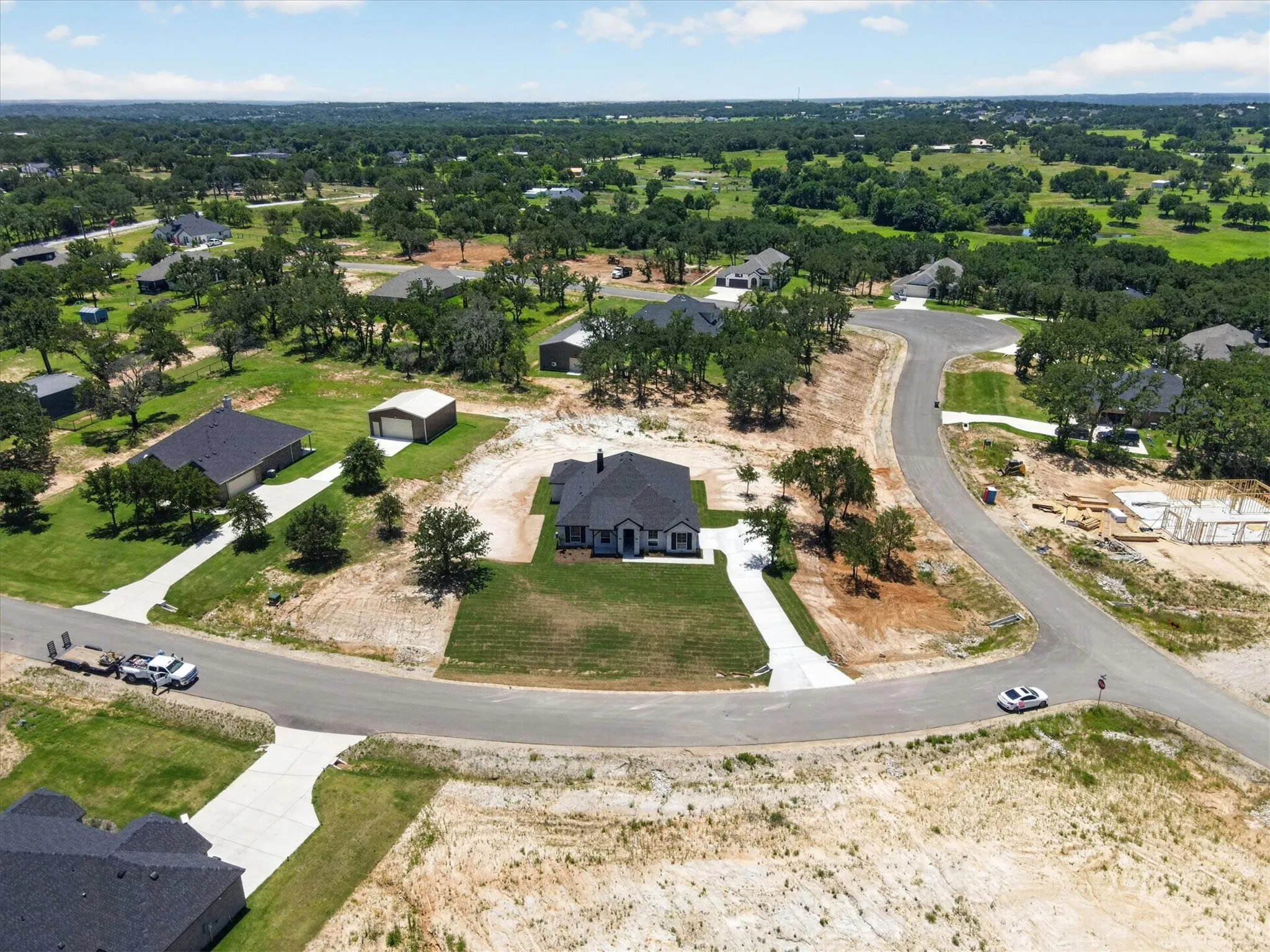 Newly constructed home featuring a dark shingle roof, white exterior siding, and a concrete driveway