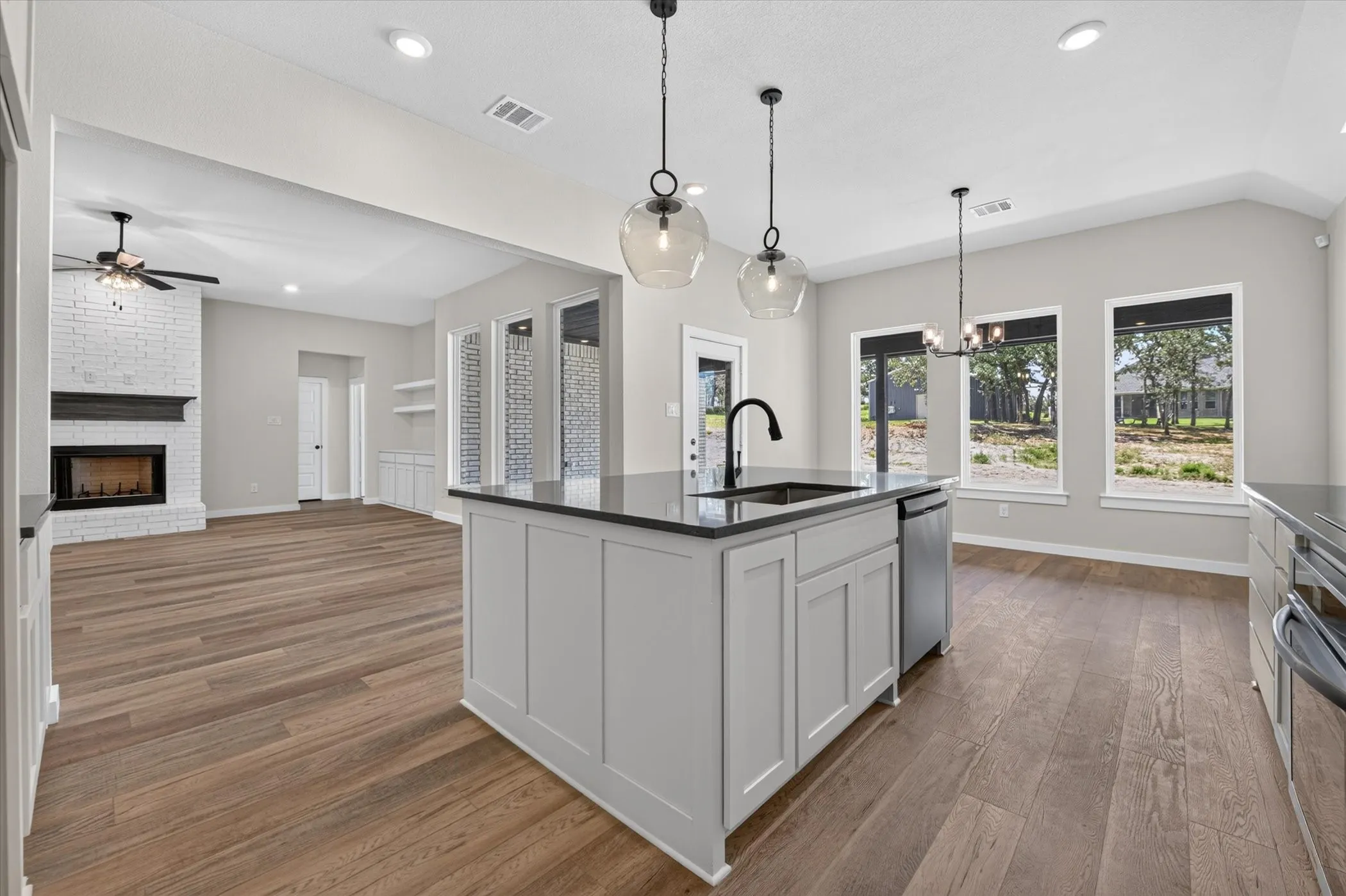 Kitchen island with integrated sink, black countertop, and pendant lighting