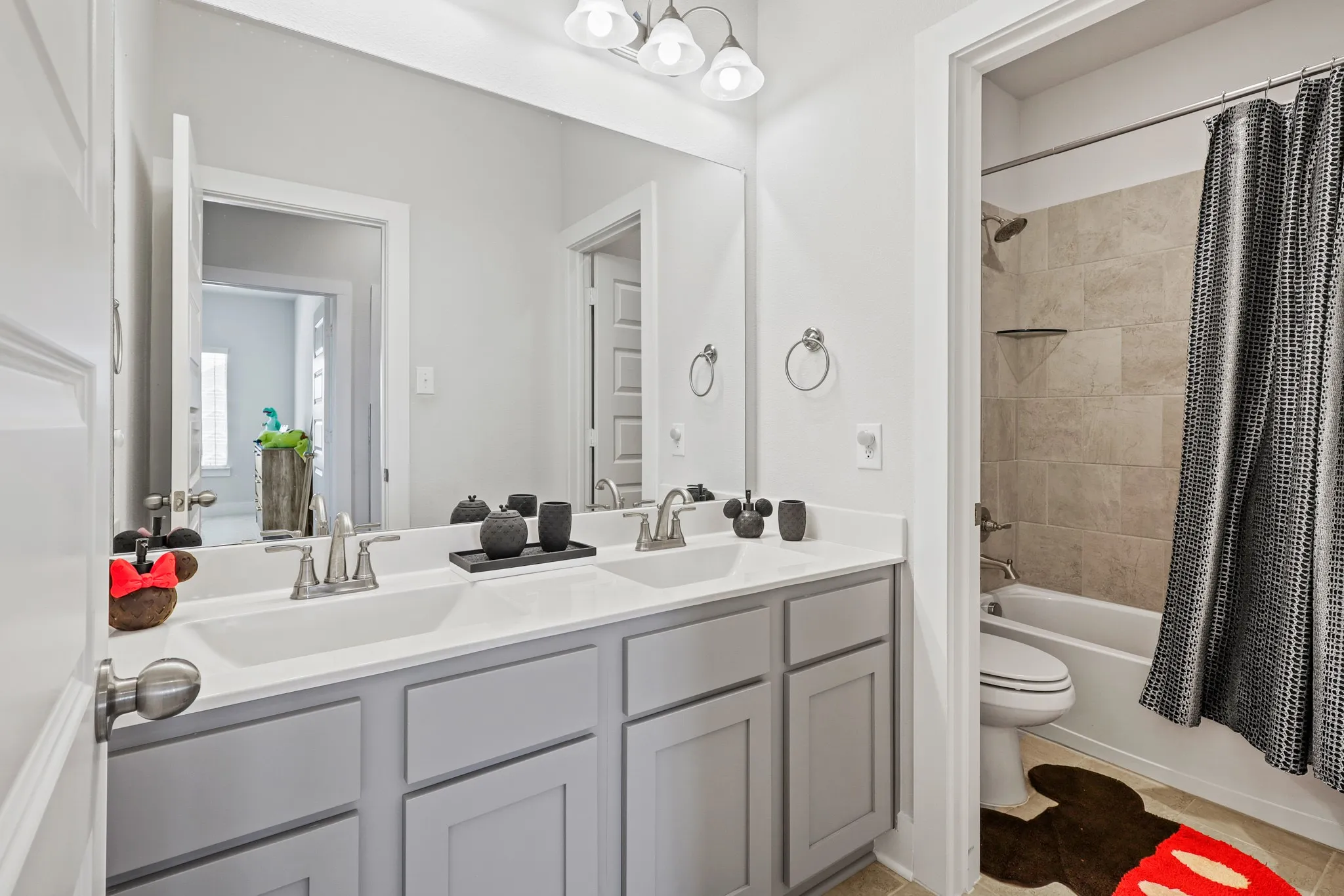 Full bathroom with dual vanity, shower / bath combo, toilet, and tile patterned floors