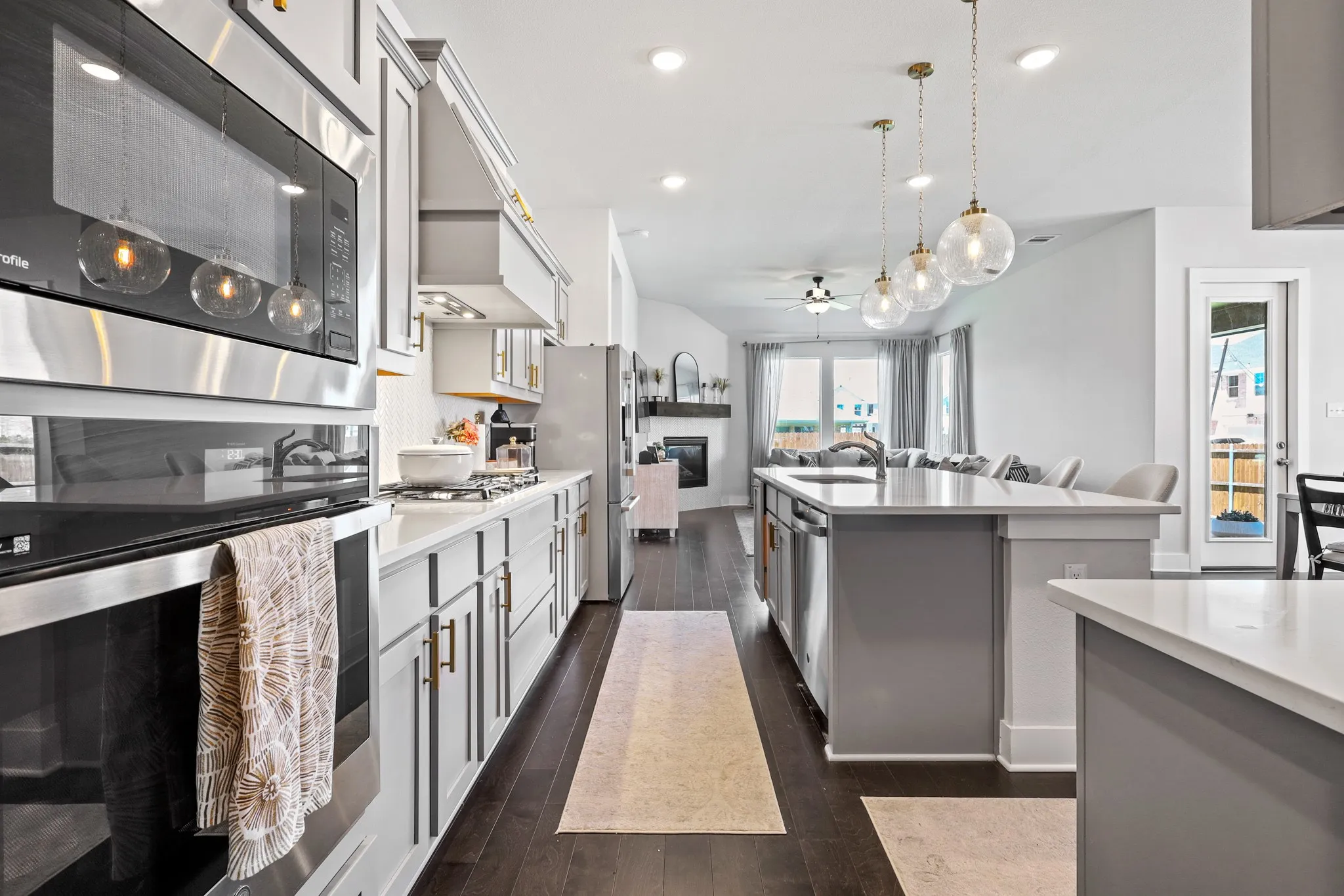 Kitchen featuring stainless steel appliances, dark hardwood / wood-style floors, sink, pendant lighting, and ceiling fan