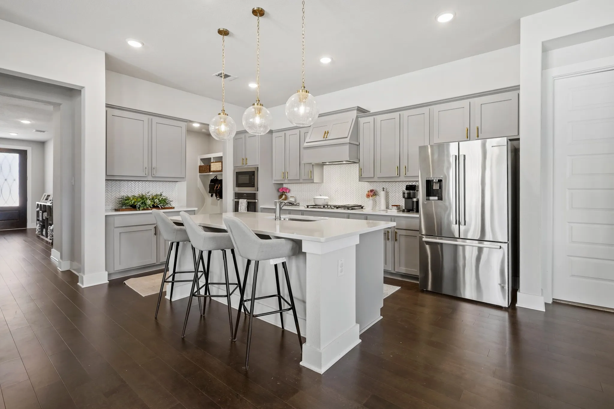 Kitchen featuring appliances with stainless steel finishes, premium range hood, dark wood-type flooring, and decorative backsplash