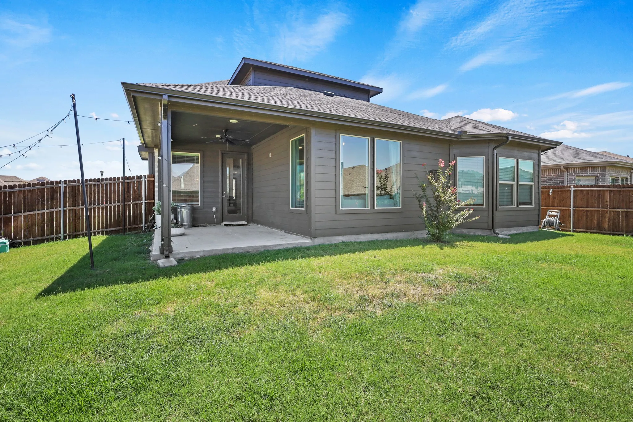 Rear view of property with ceiling fan, a patio, and a lawn