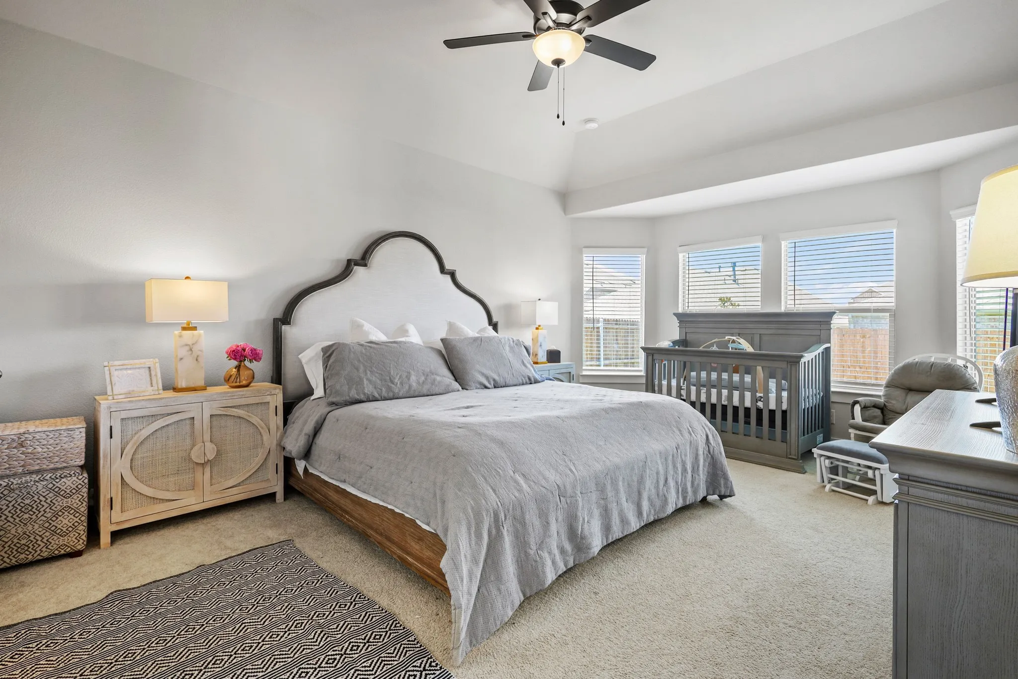 Carpeted bedroom featuring ceiling fan, lofted ceiling, and multiple windows