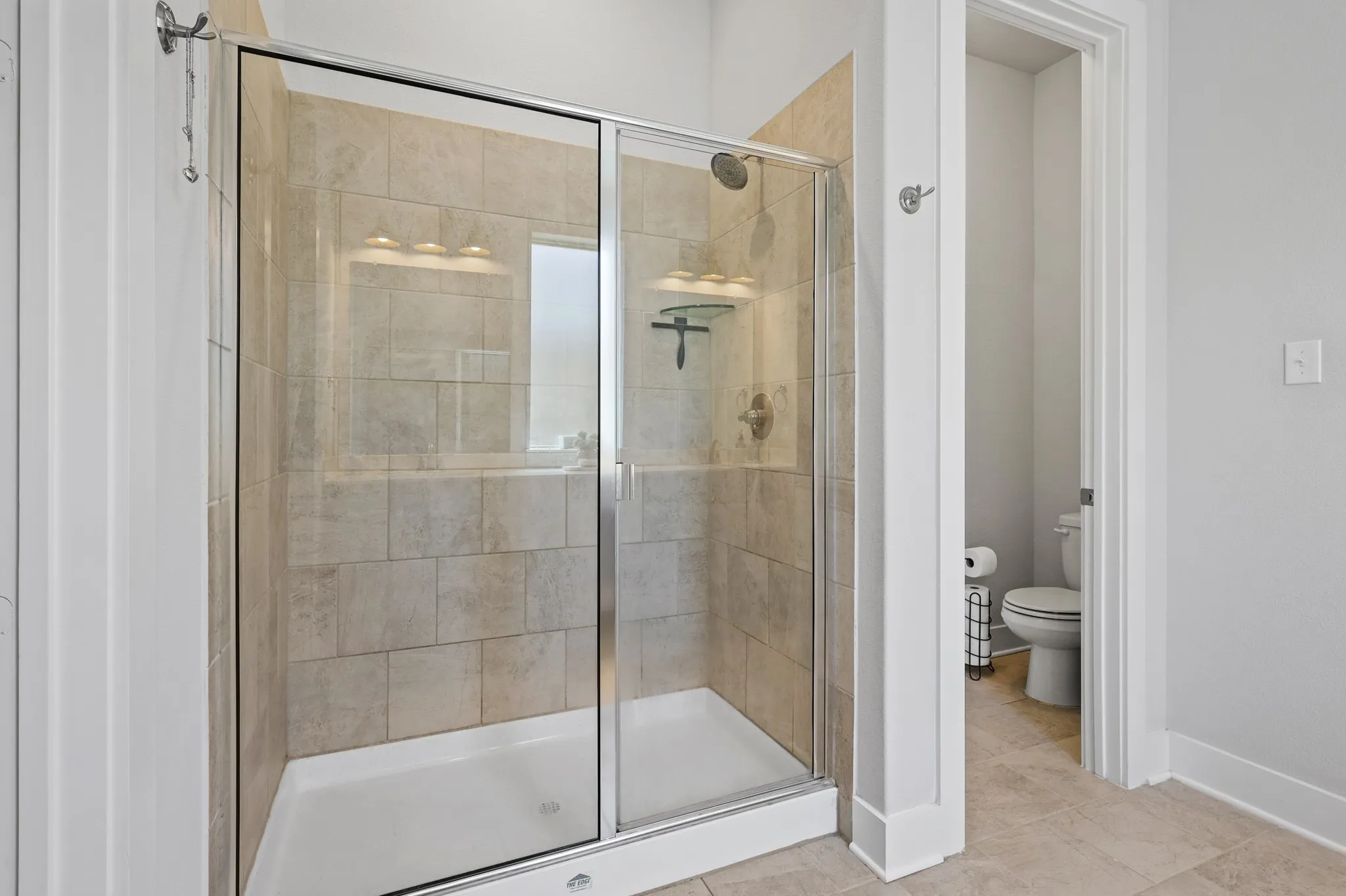 Bathroom featuring tile patterned flooring, toilet, and a shower with door