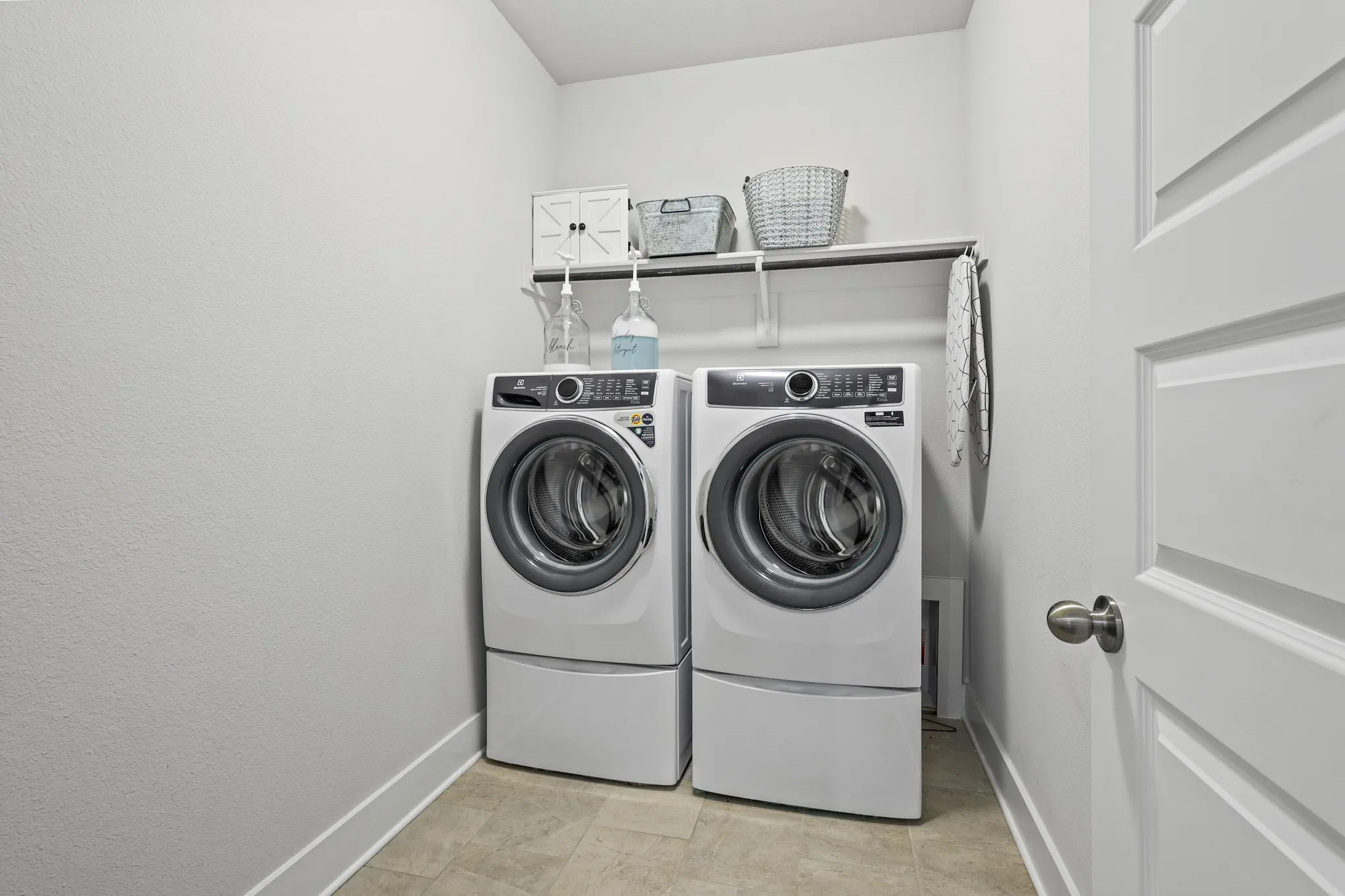 Washroom with washing machine and dryer and light tile patterned floors