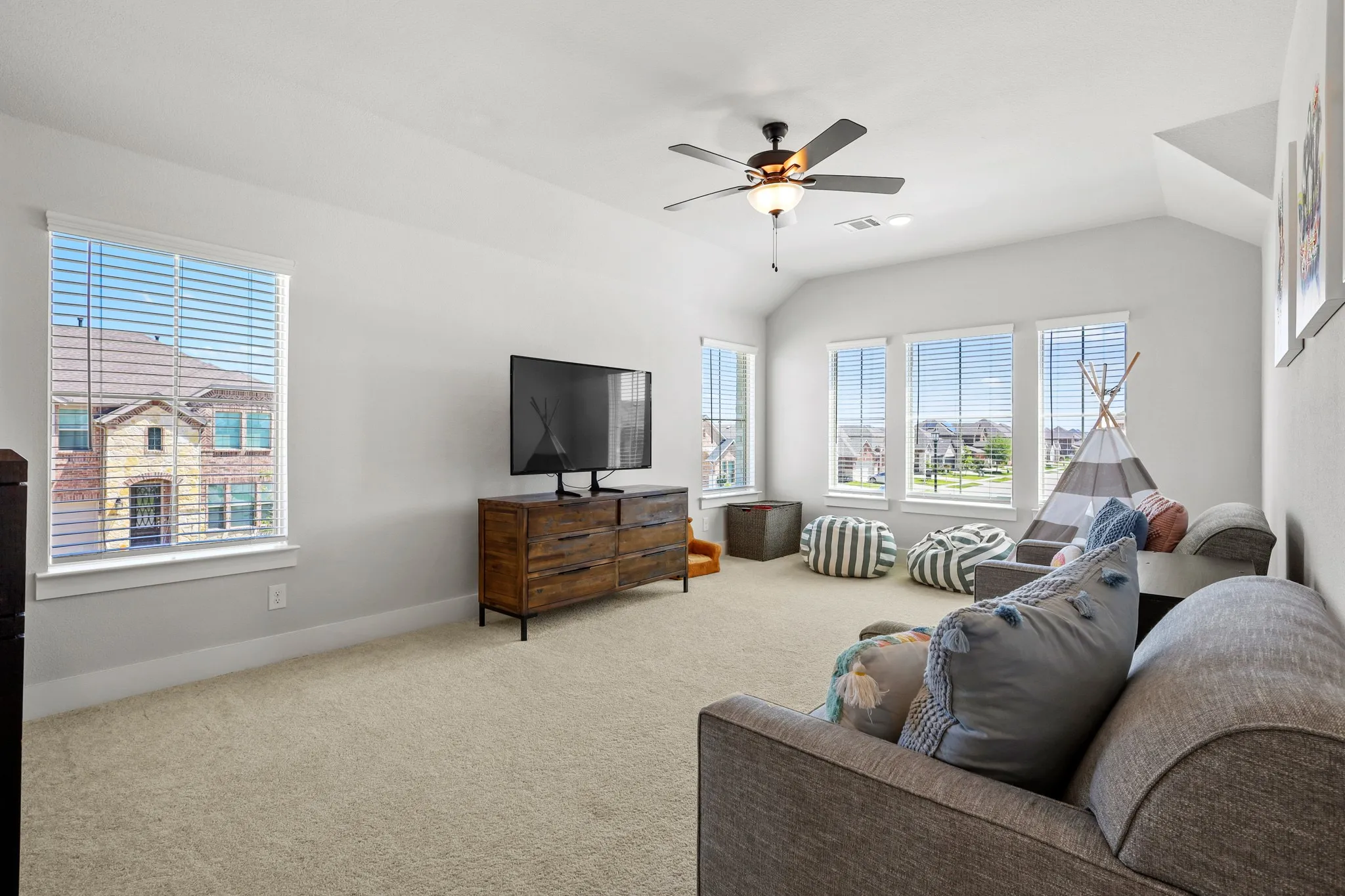 Carpeted living room with ceiling fan and vaulted ceiling