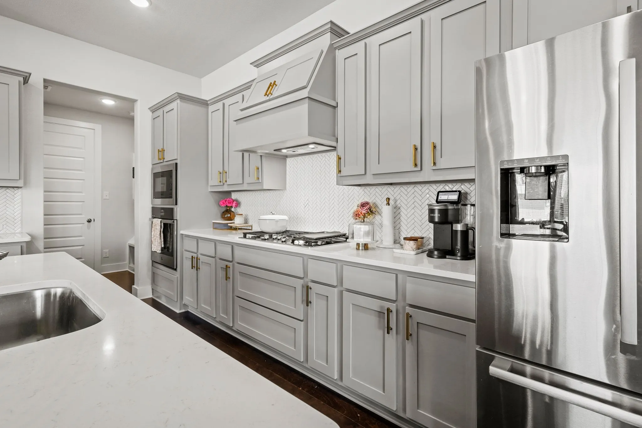 Kitchen featuring custom range hood, stainless steel appliances, gray cabinets, and tasteful backsplash