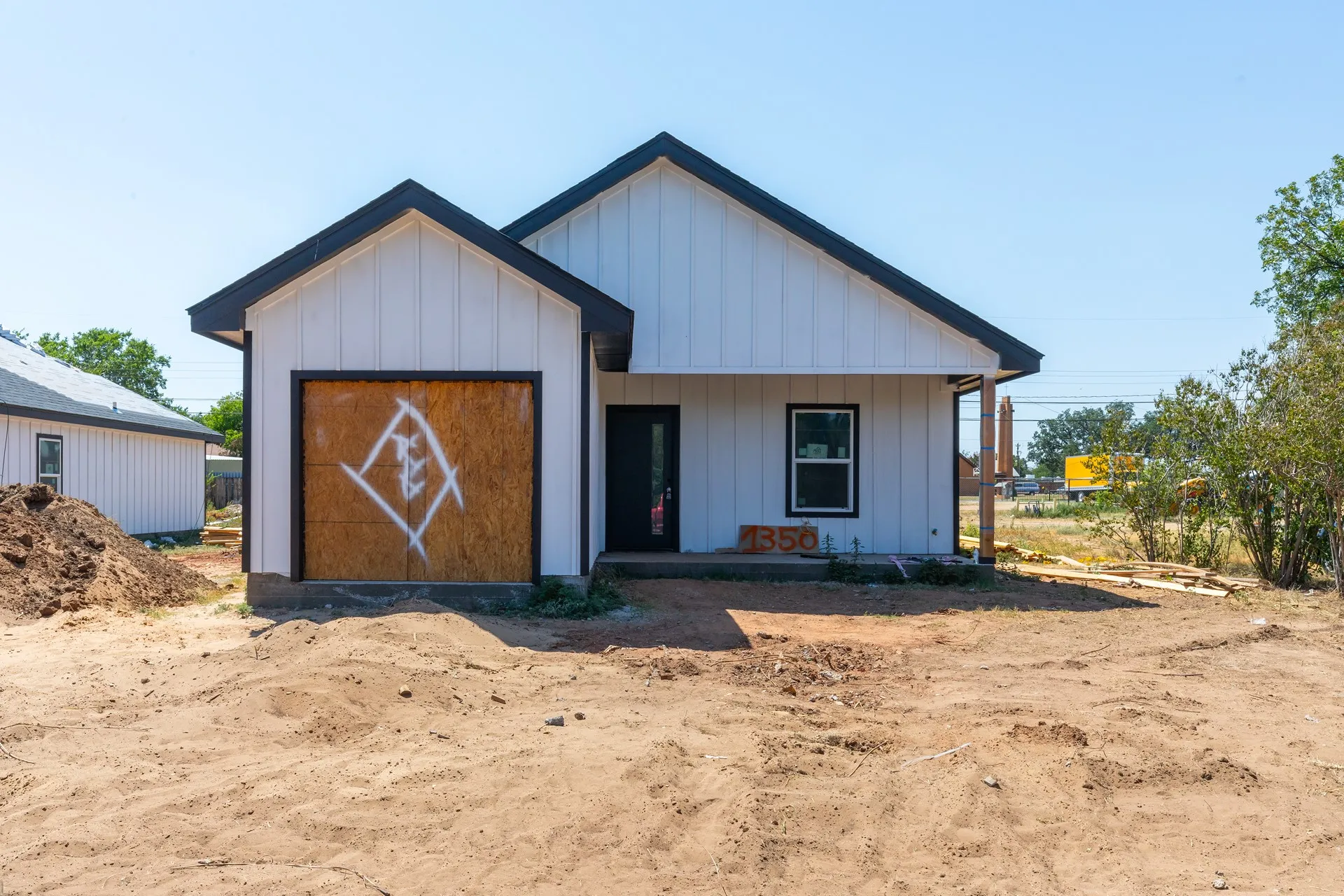 White vertical plank siding with black trim, black roof, and a black front entry door