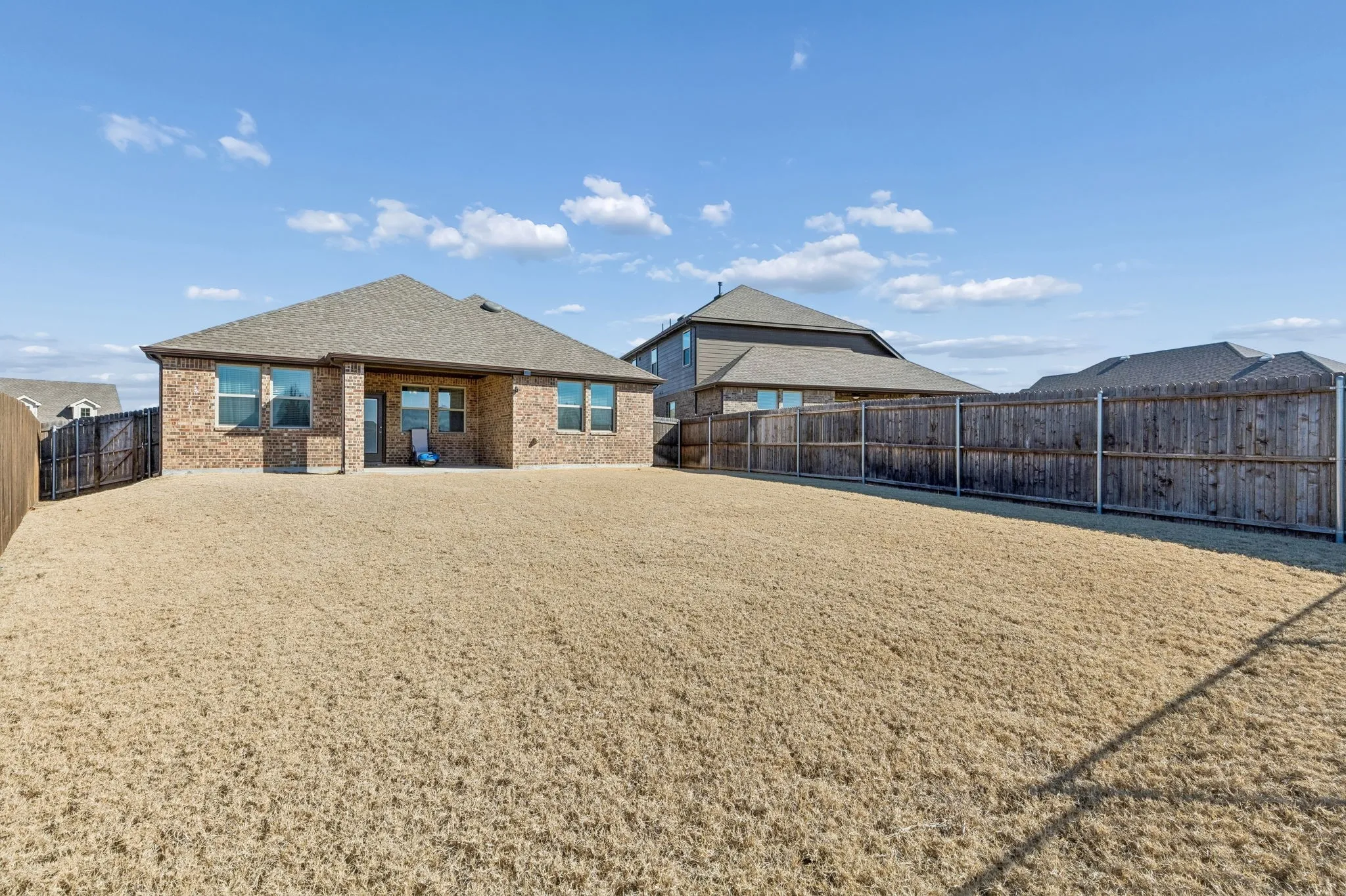 Rear view of house featuring a fenced backyard, brick siding, a patio, and a shingled roof